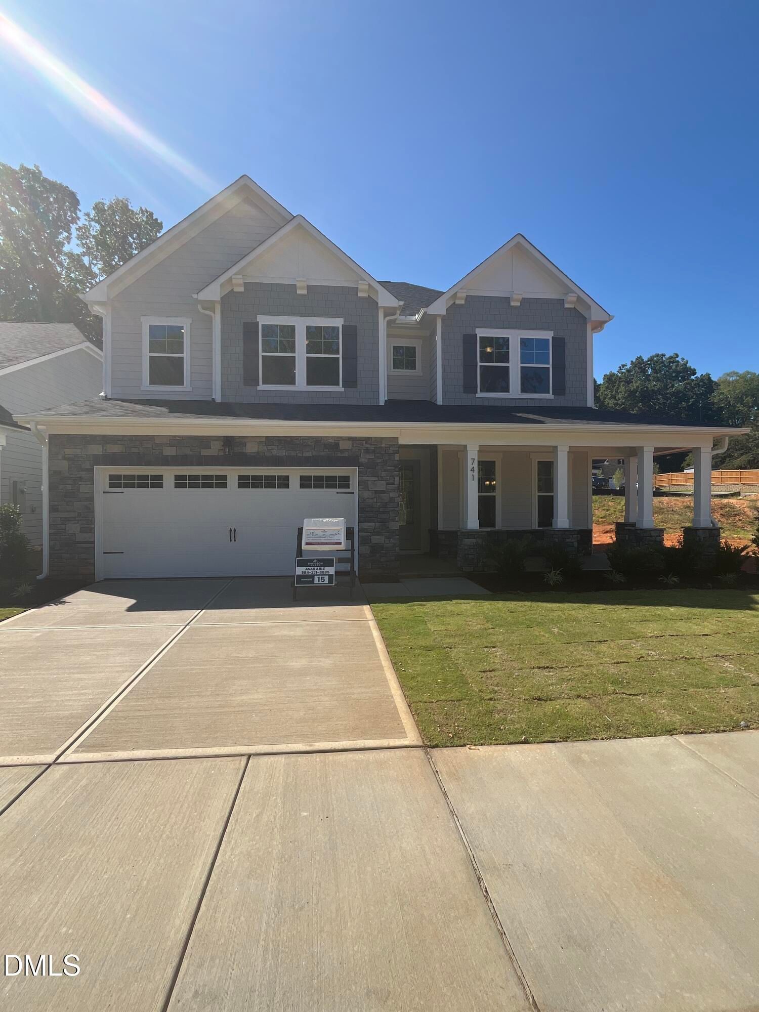Two-story gray and stone new construction home with covered porch and 2-car garage in Sage on North Main, Wake Forest, NC