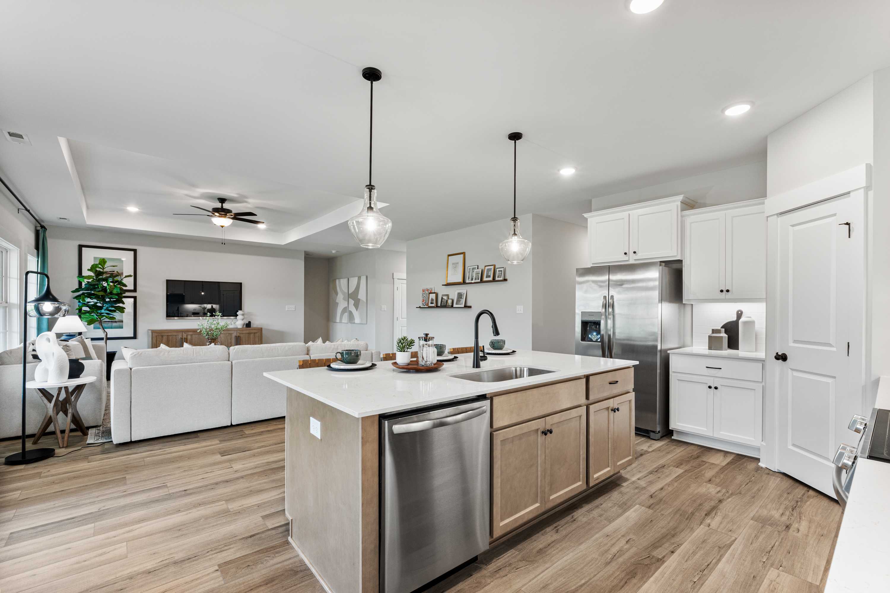 Open-concept kitchen and living area at River Road Estates in Decatur Alabama with white cabinets, center island, hardwood floors