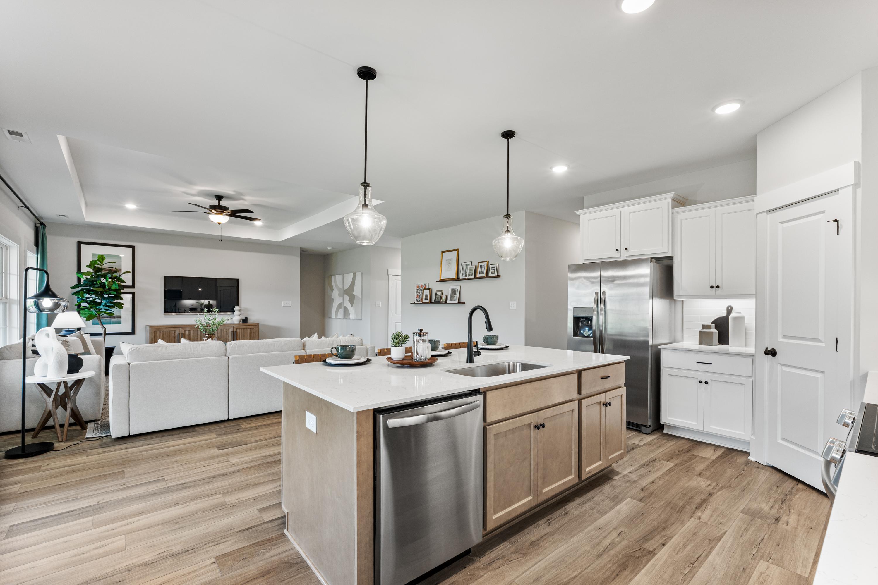 Open-concept kitchen and living area at River Road Estates in Decatur Alabama with white cabinets, center island, hardwood floors
