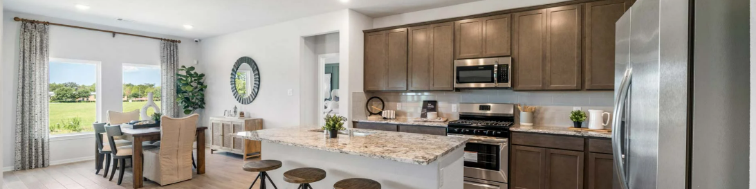 Spacious open-concept kitchen with granite island, stainless appliances, and dining area in new Splendora home