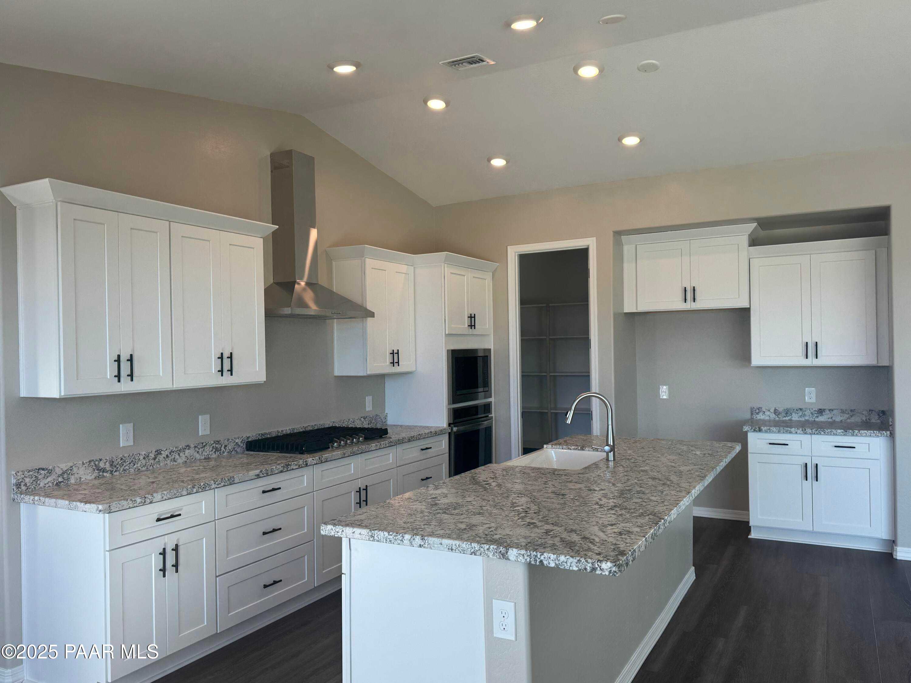 Elegant kitchen with white shaker cabinets, granite island sink, stainless double ovens in Davidson Homes The Monarch E, Prescott AZ