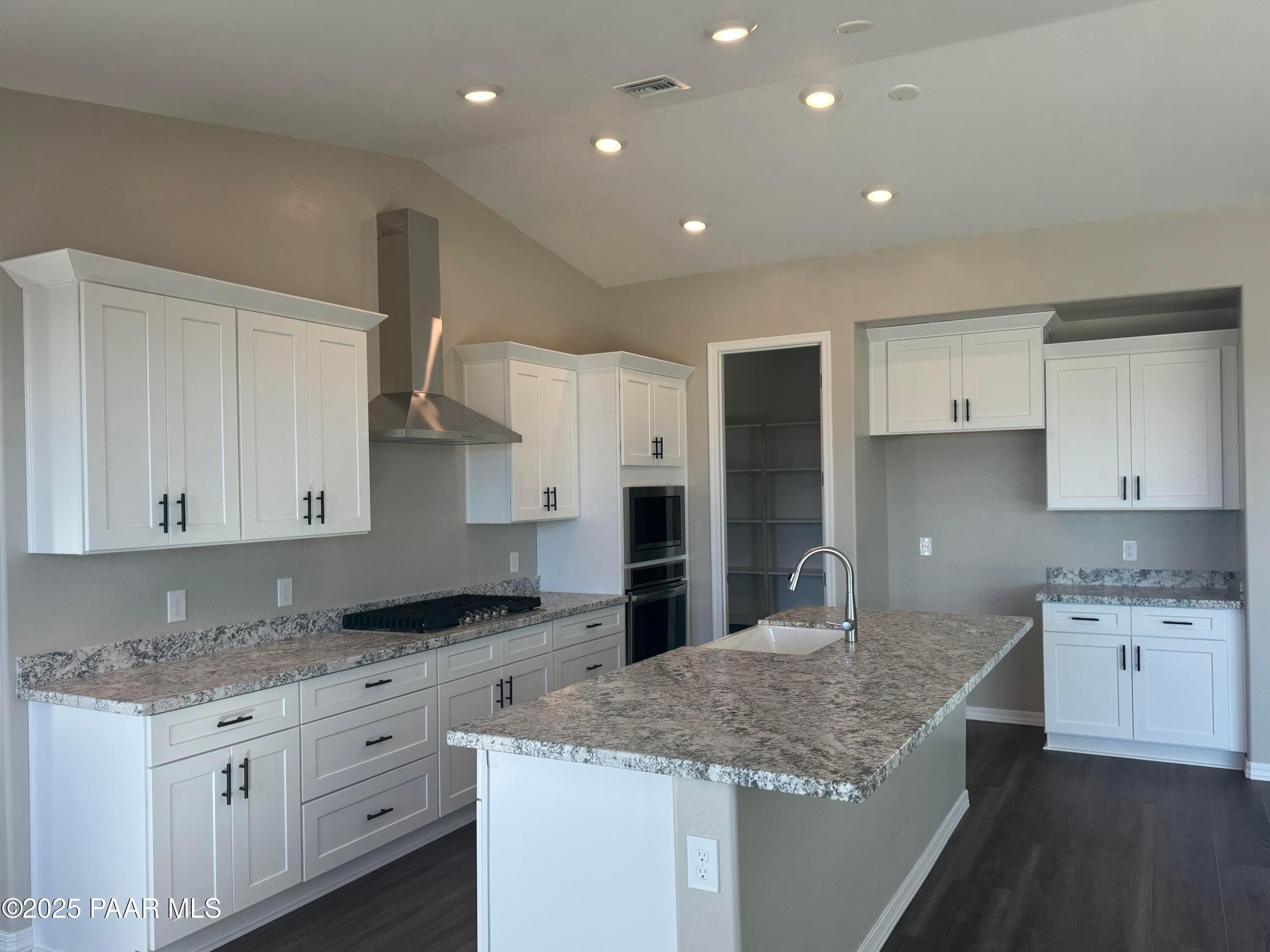 Elegant kitchen with white shaker cabinets, granite island sink, stainless double ovens in Davidson Homes The Monarch E, Prescott AZ