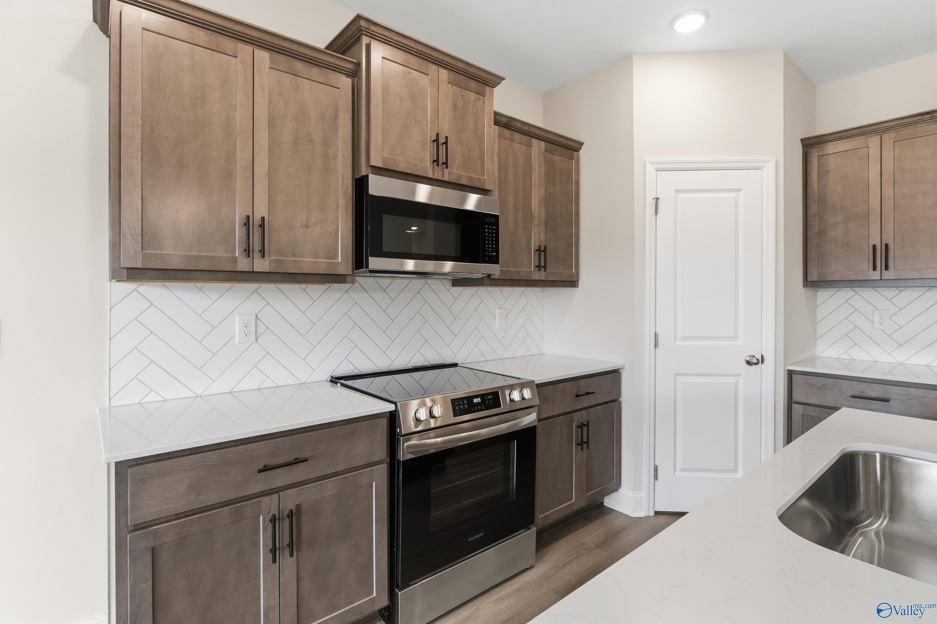Modern kitchen featuring gray shaker cabinets, stainless steel appliances, herringbone backsplash in The Asheville C by Davidson Homes, Huntsville AL