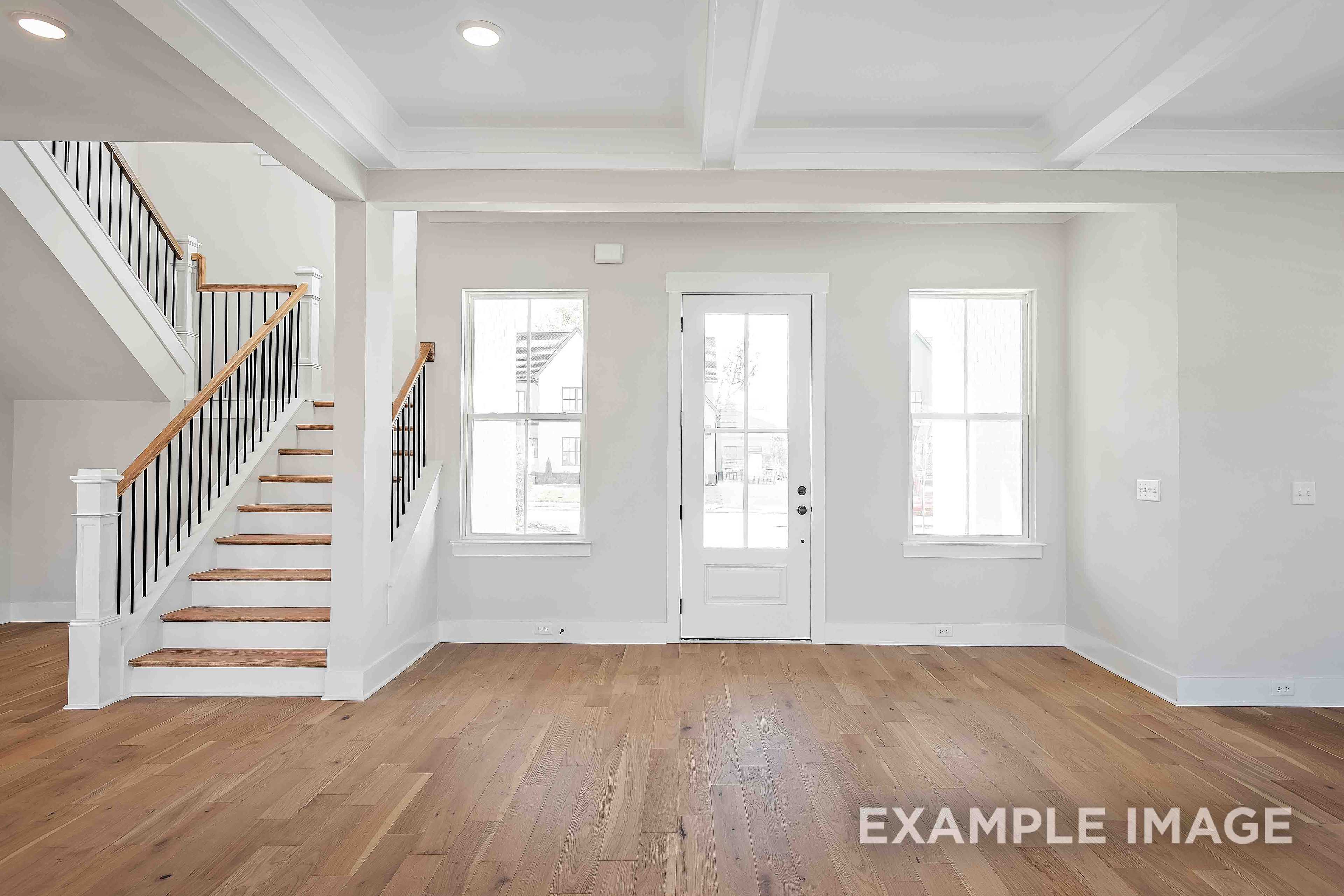 Spacious entry foyer in The Alston A featuring grand oak staircase, French doors, and large windows, Davidson Homes 2-story design