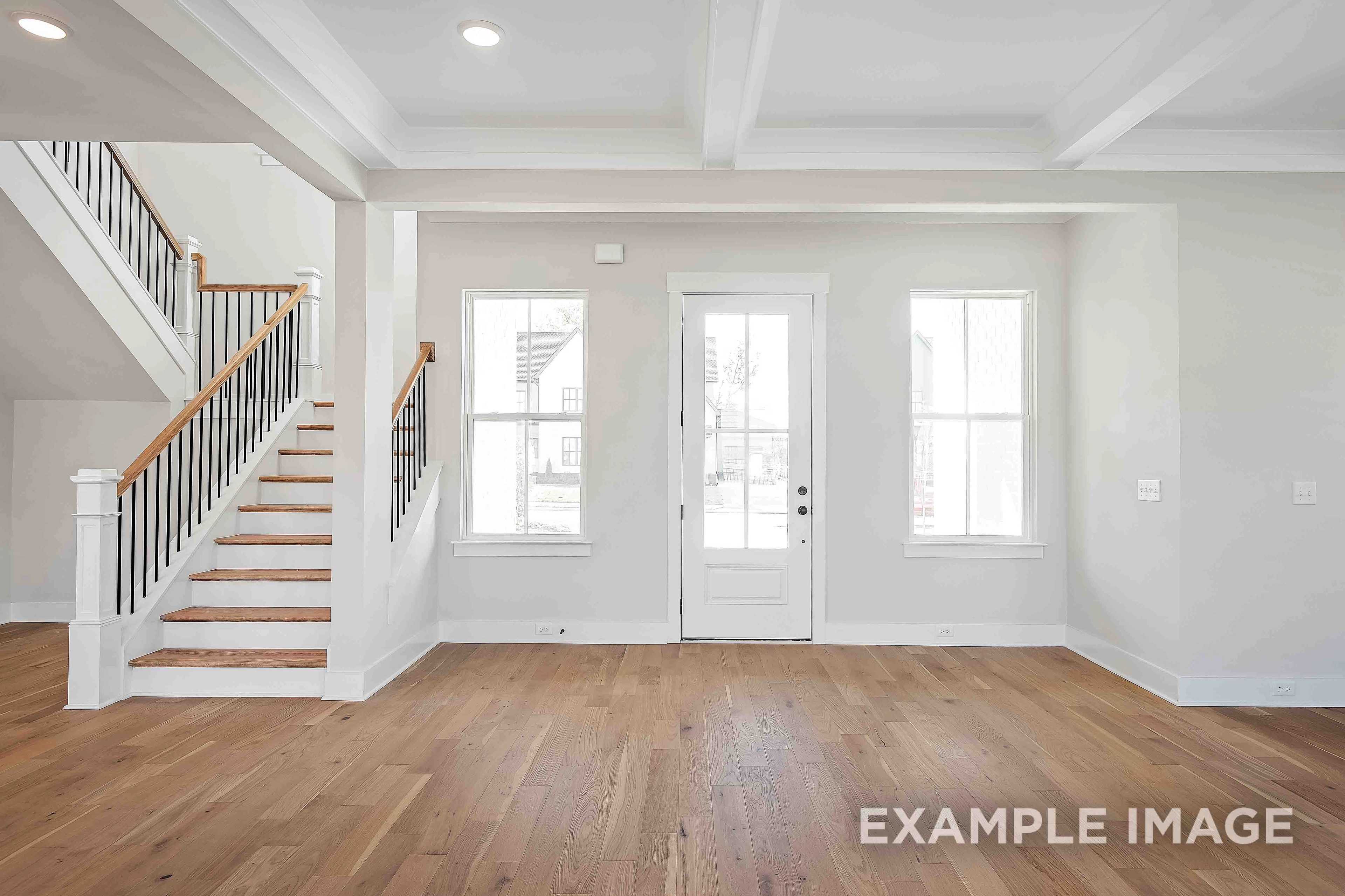 Spacious entry foyer in The Alston A featuring grand oak staircase, French doors, and large windows, Davidson Homes 2-story design