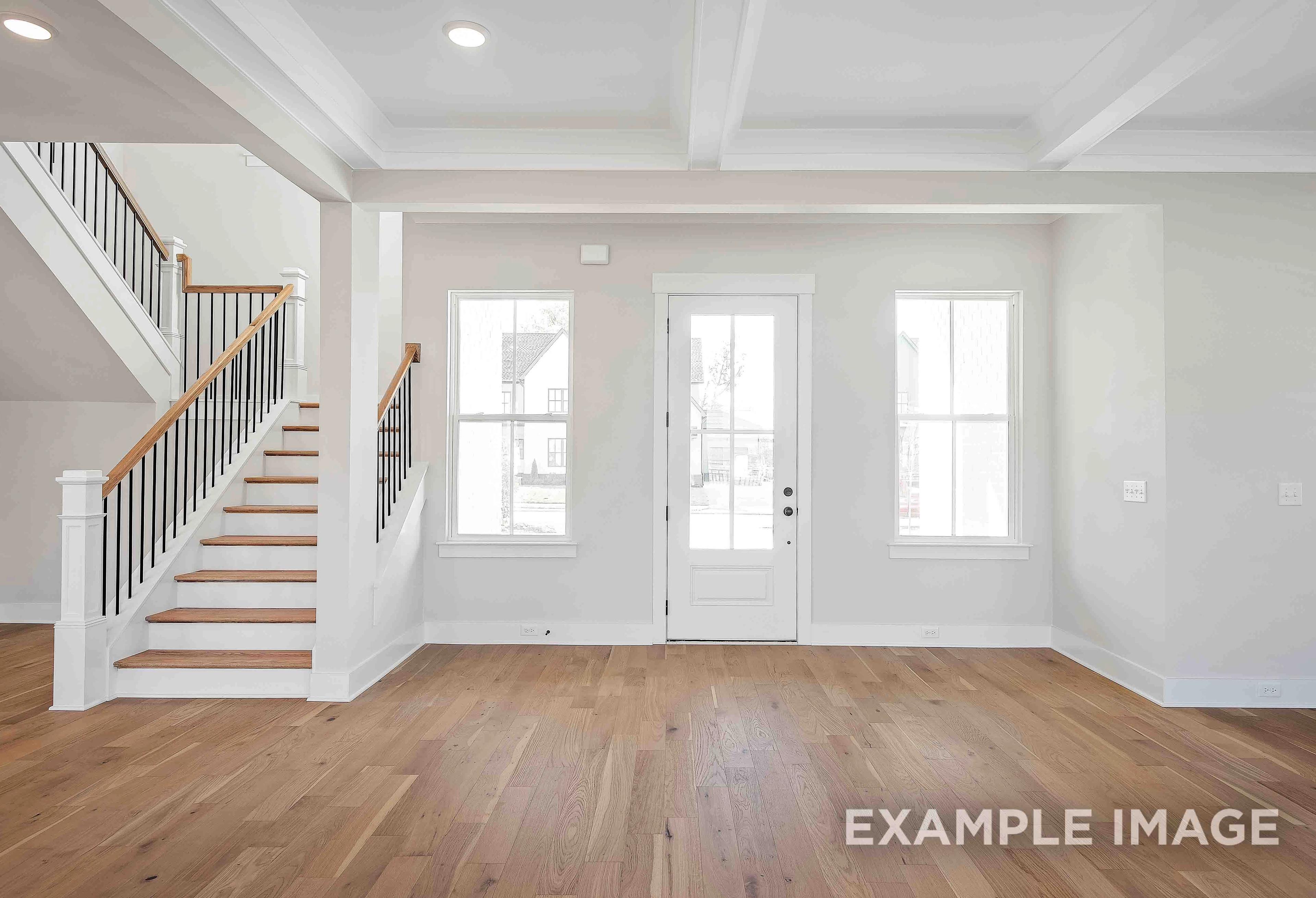 Spacious entry foyer in The Alston A featuring grand oak staircase, French doors, and large windows, Davidson Homes 2-story design