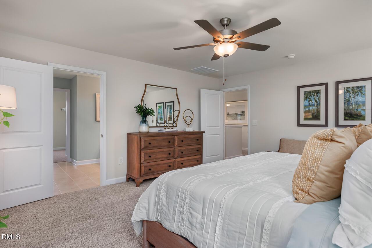 Cozy bedroom with wooden dresser and ceiling fan in The Willow B floor plan by Davidson Homes in Montrose, Aberdeen, NC.