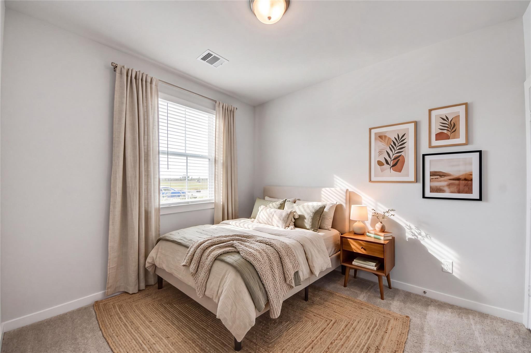 Cozy bedroom with neutral bedding and gallery wall in Davidson Homes The Costa A, 3-bedroom home in Emberly, Beasley, Texas