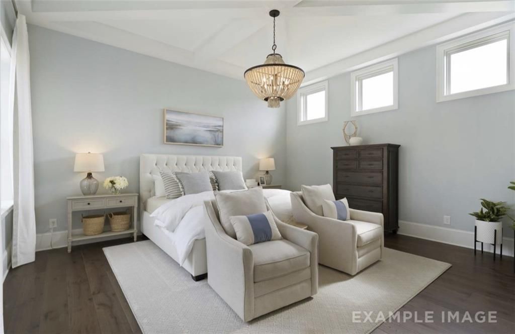 Elegant master bedroom with tufted king bed, beige armchairs, chandelier, and clerestory windows in Davidson Homes Seaside A, Woodstock GA