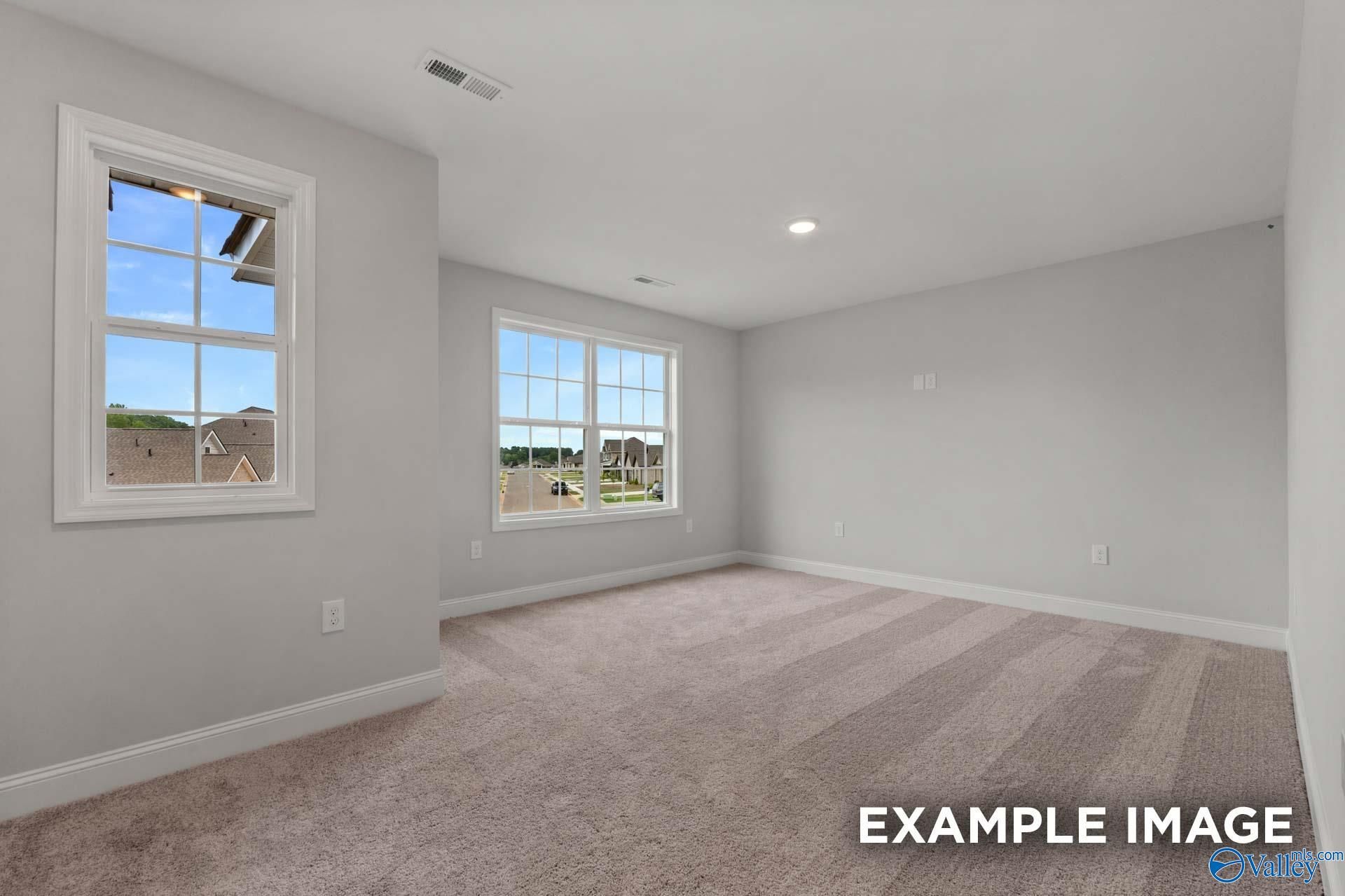 Bright empty bedroom with light gray walls, beige carpet, and large windows overlooking neighborhood in The Shelby C home, Arab, Alabama