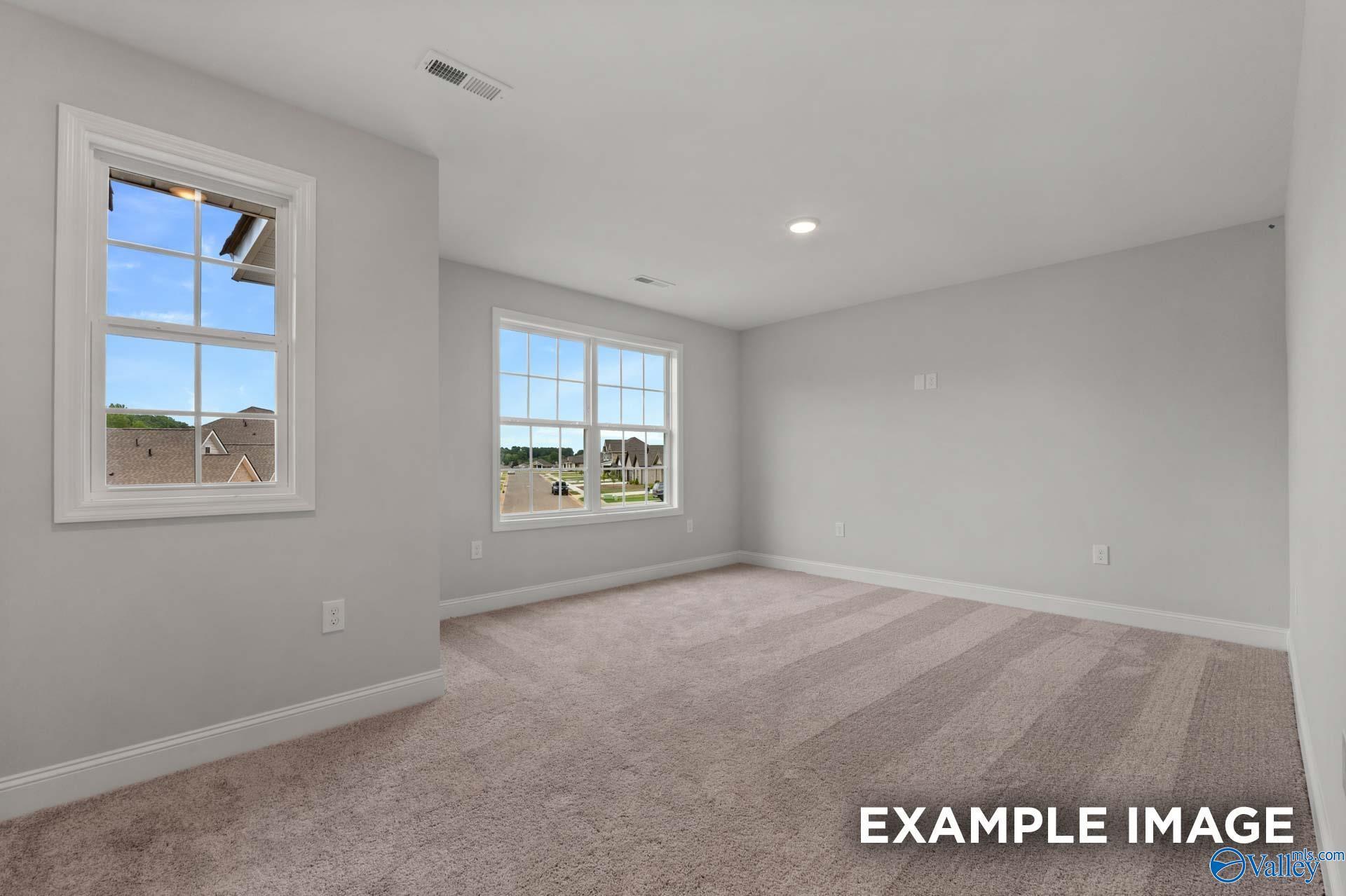 Bright empty bedroom with light gray walls, beige carpet, and large windows overlooking neighborhood in The Shelby C home, Arab, Alabama