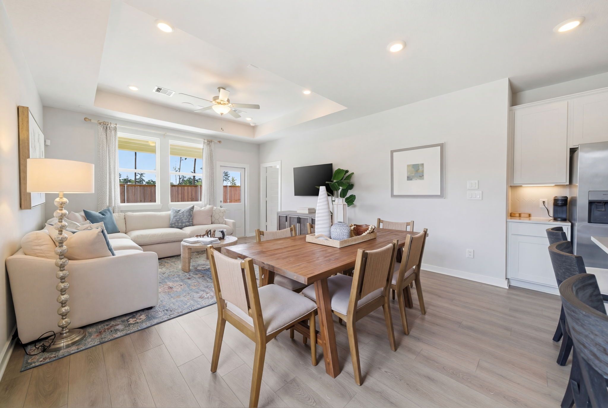 Spacious open-concept living and dining area at Spring Branch Crossing in Conroe Texas with hardwood floors, white sofa, wooden table, and ceiling fan