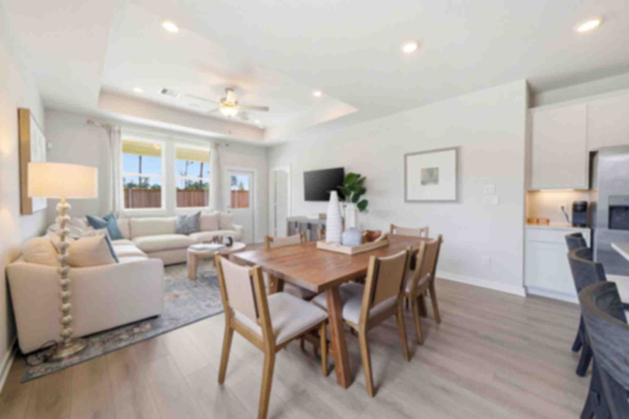 Open-concept living room and kitchen at Spring Branch Crossing in Conroe Texas featuring pink armchairs, hardwood floors, and white cabinetry