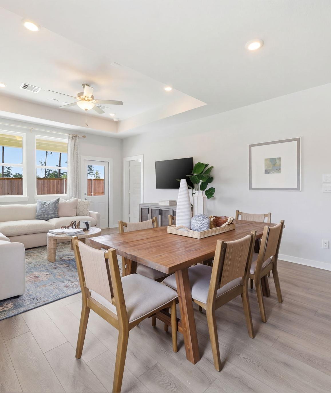 Open-concept living room and kitchen at Spring Branch Crossing in Conroe Texas featuring pink armchairs, hardwood floors, and white cabinetry