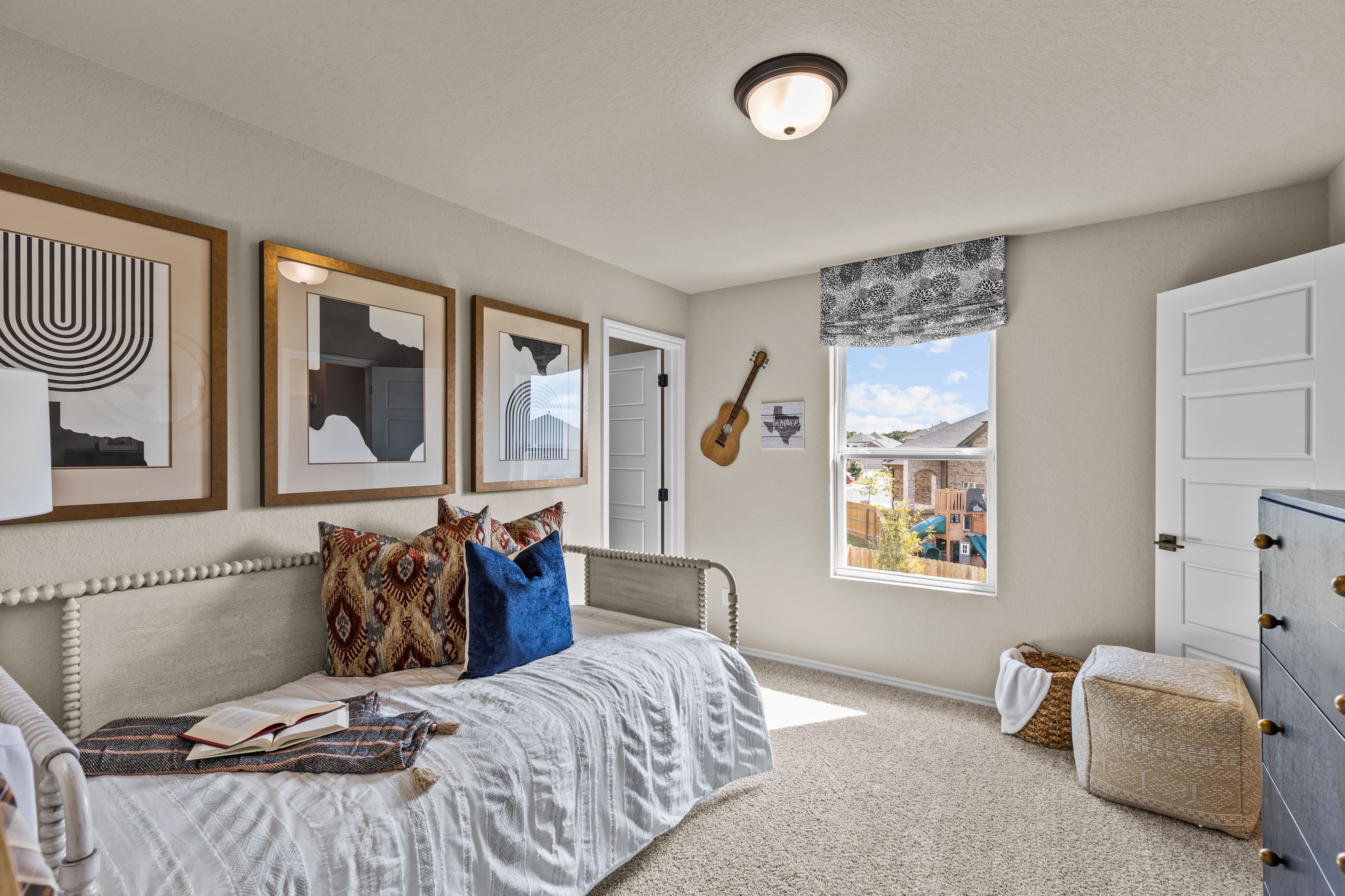 Cozy bedroom interior at Morgan Meadows in San Antonio Texas with daybed, abstract wall art, guitar, and window view