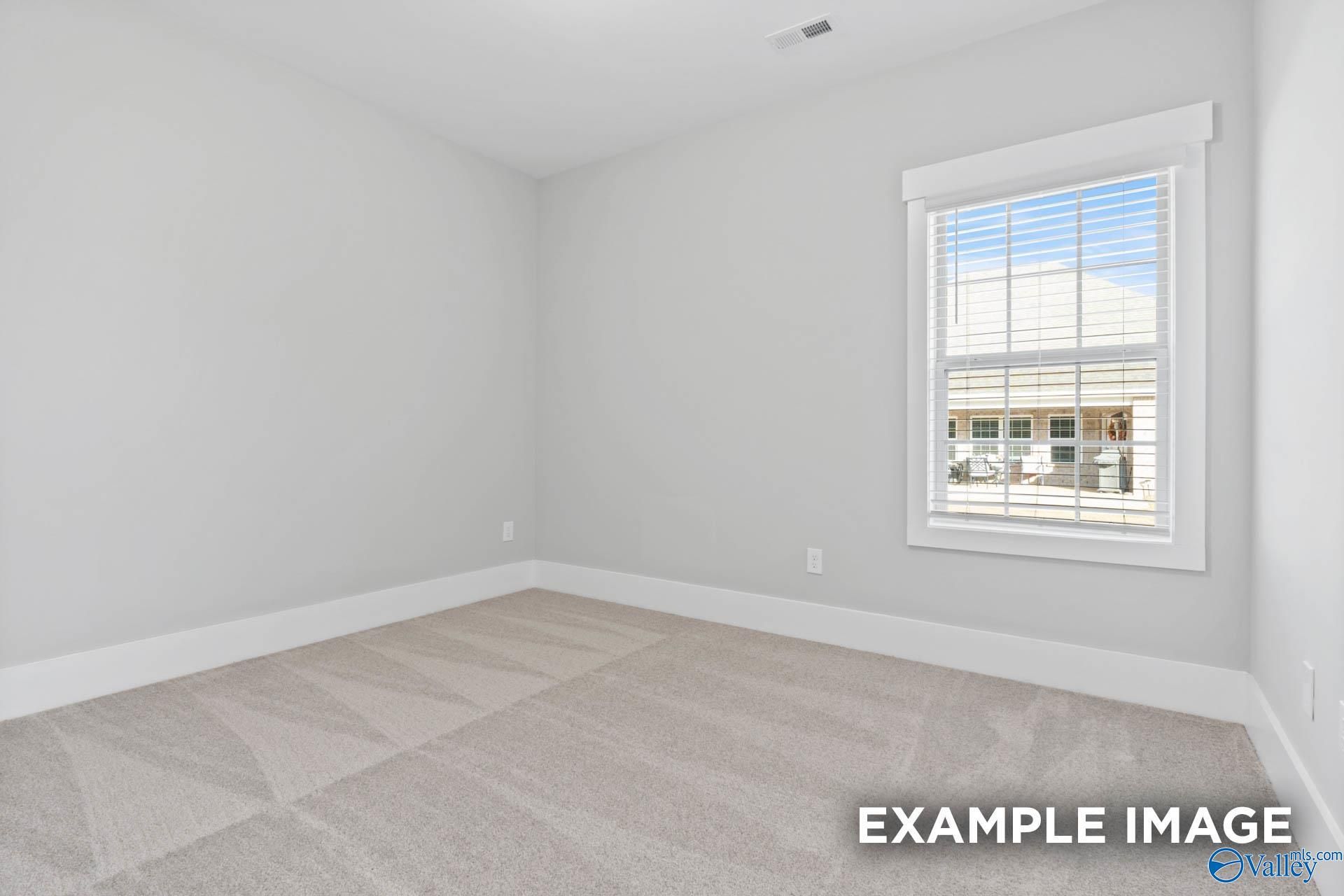 Empty secondary bedroom featuring light gray walls, neutral carpet, and large window in Davidson Homes The Rockford, Meridianville, Alabama