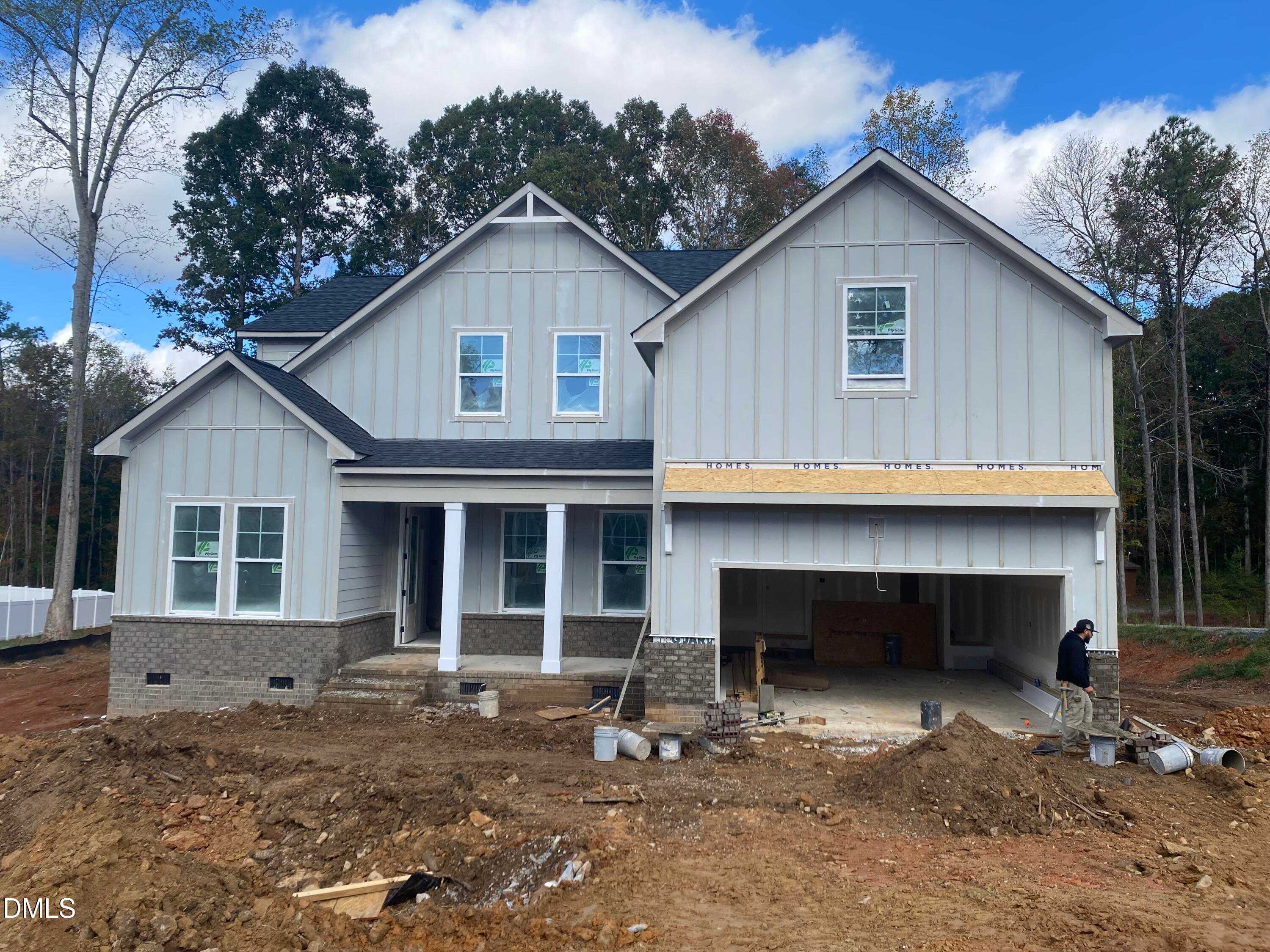 Two-story gray Crawford C home by Davidson Homes in Laneridge Estates, Raleigh, NC, with front porch, open two-car garage, and wooded surroundings
