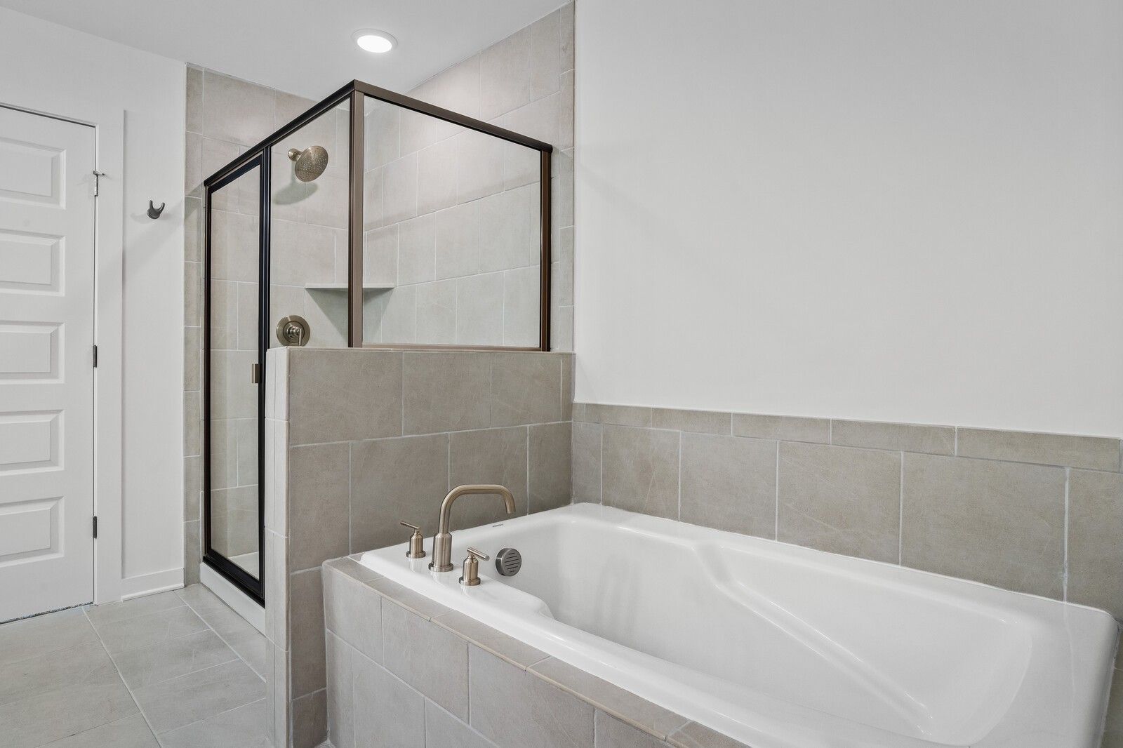Modern bathroom with tiled soaking tub and enclosed glass shower in The Logan C floor plan at Calista Farms, White House, TN.
