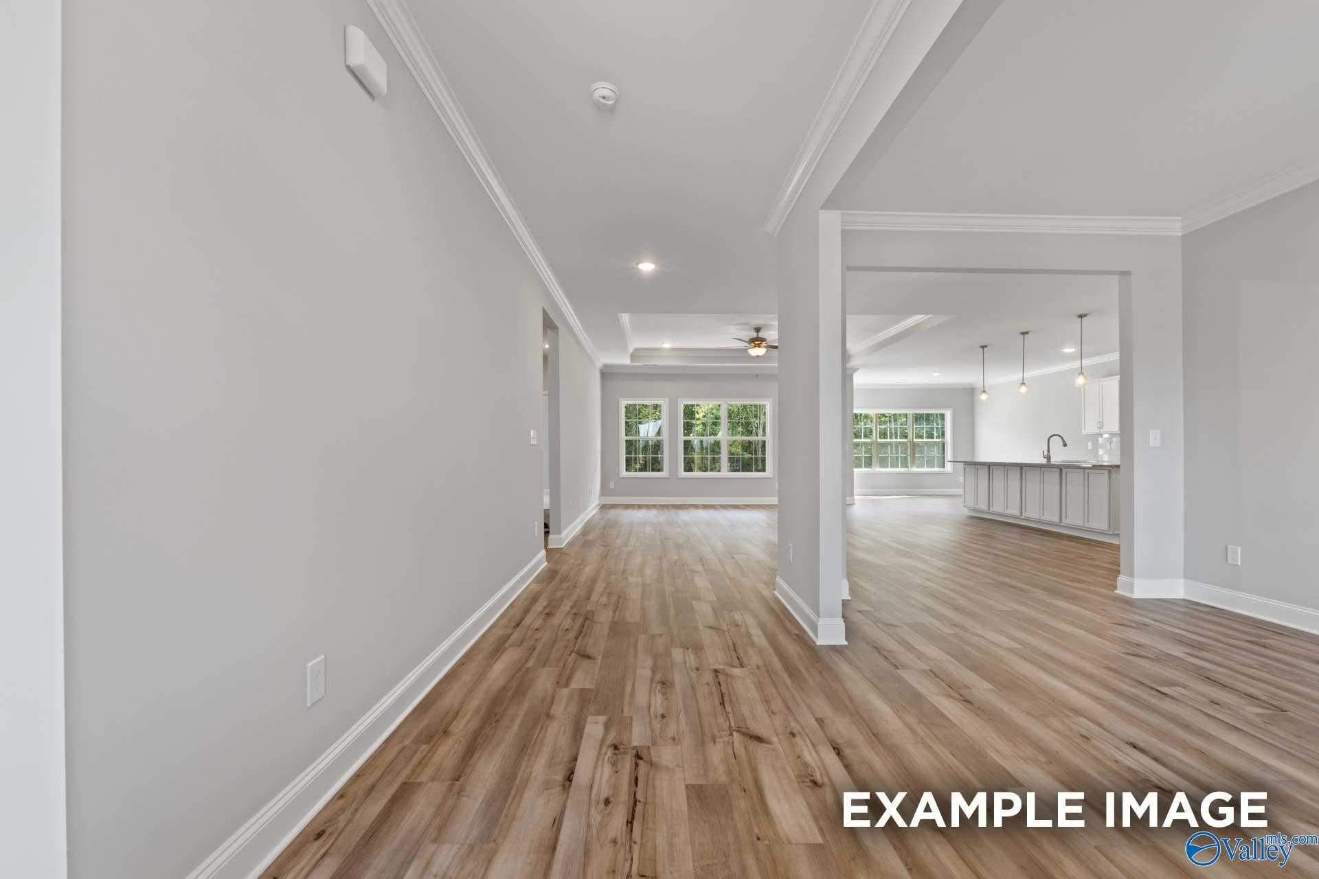 Bright hallway with oak hardwood floors opening to modern white kitchen in Davidson Homes The Richmond D, Huntsville, AL
