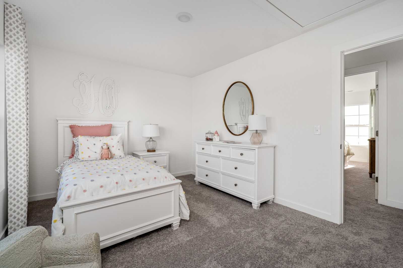 Charming girl's bedroom with pink twin bed, white dresser, gold mirror in Davidson Homes The Cumberland A, Gallatin, TN