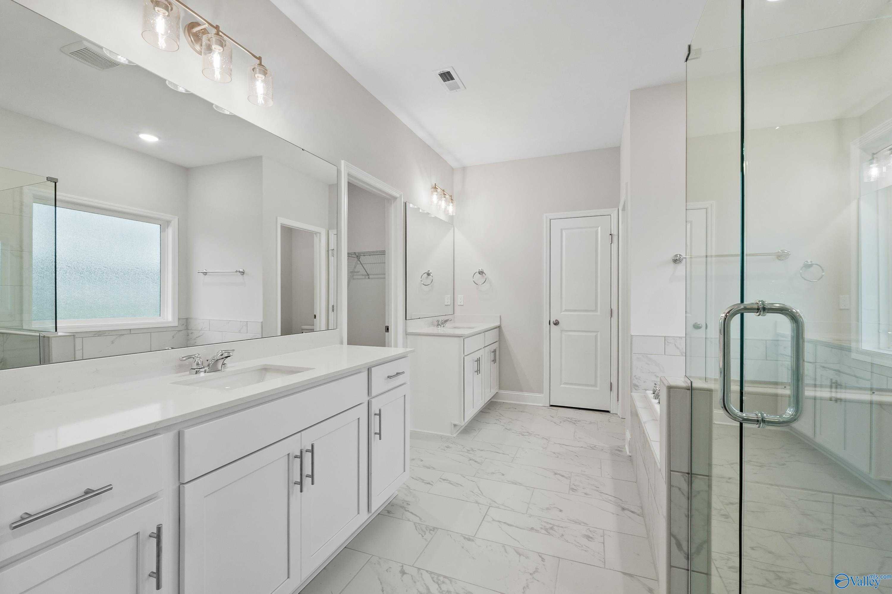 Modern master bathroom with double white vanity, glass shower, soaking tub in Davidson Homes The Lanier, Harvest AL