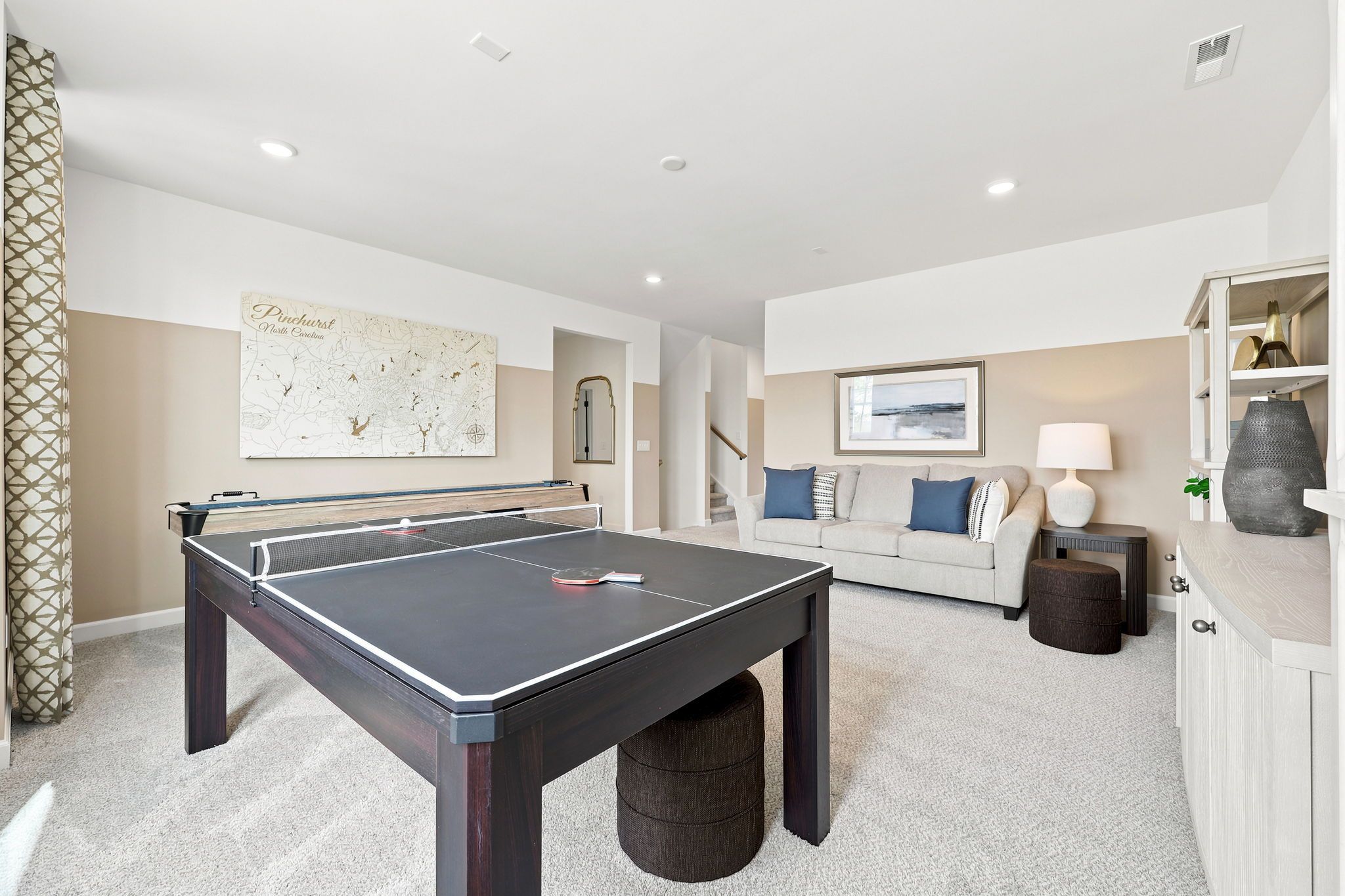 Spacious game room at Montrose in Aberdeen, NC by Davidson Homes featuring a ping pong table, lounge area, and sofa.