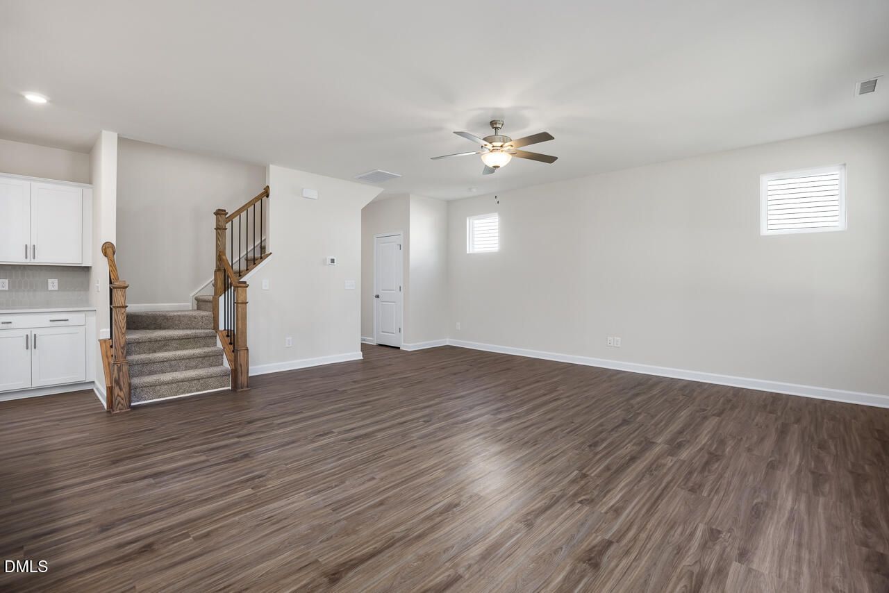 Spacious two-story entryway with oak staircase, ceiling fan, and hardwood floors in The Grace C home, Lillington NC
