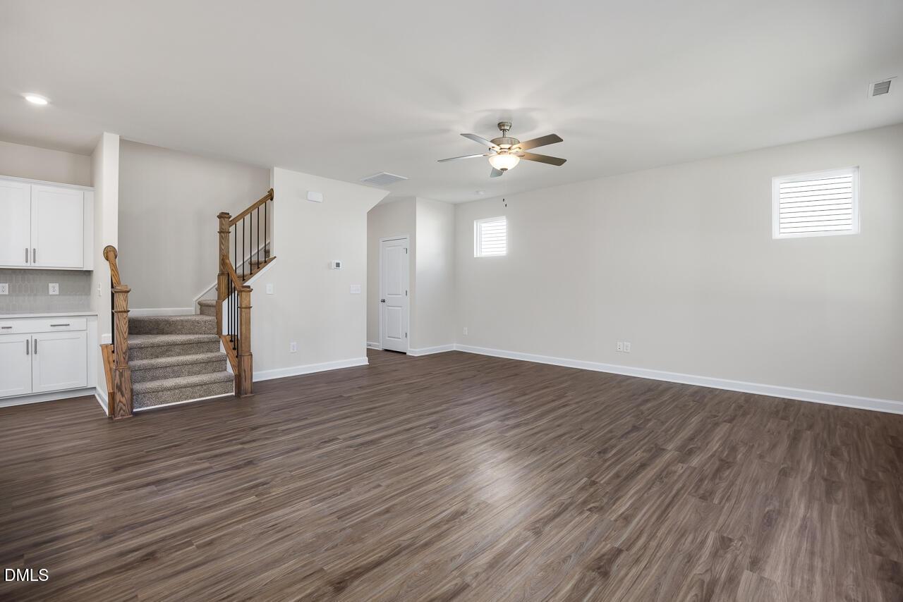 Spacious two-story entryway with oak staircase, ceiling fan, and hardwood floors in The Grace C home, Lillington NC