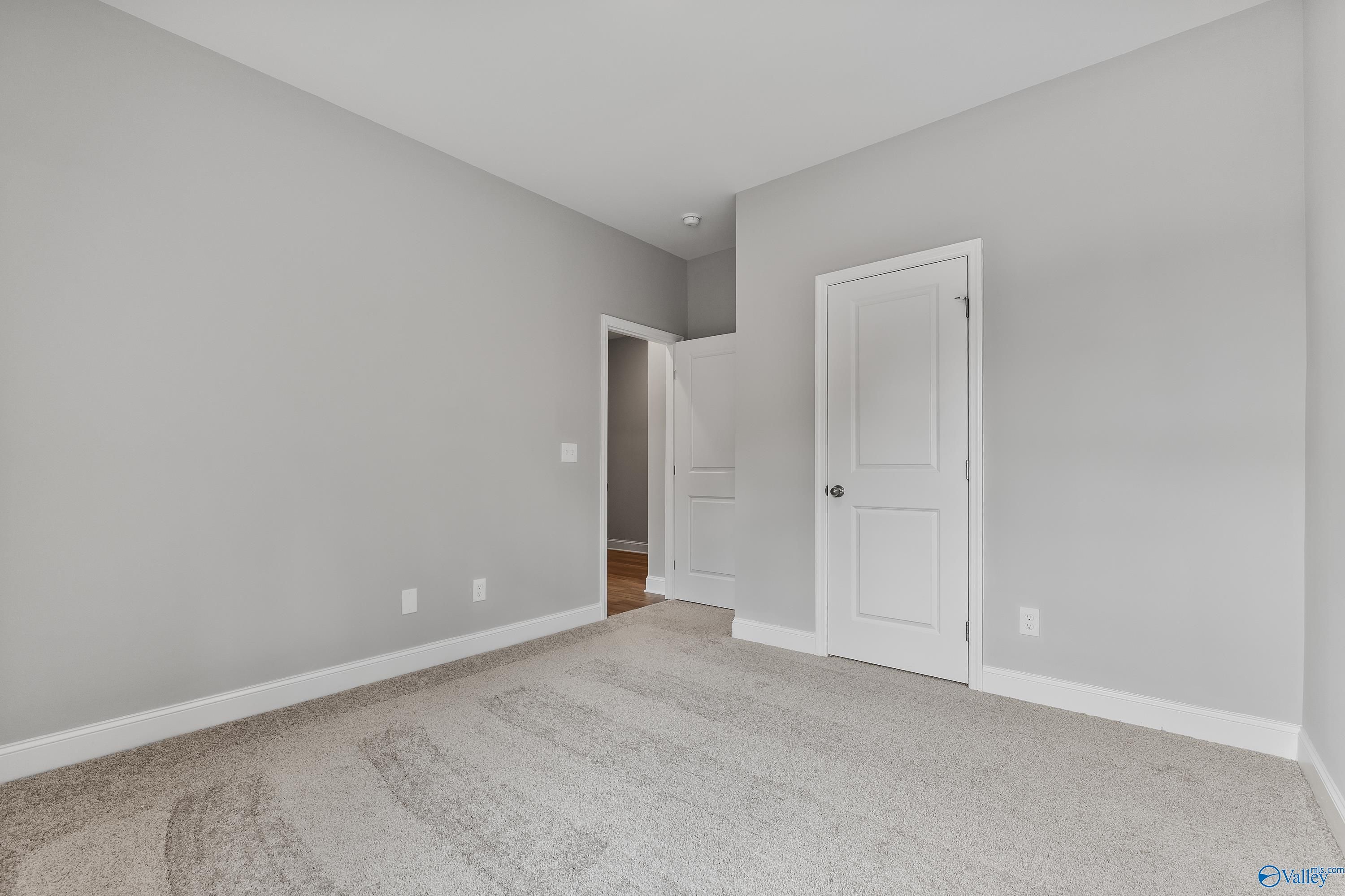 Spacious bedroom with gray walls, white doors, and plush carpet in The Franklin 3-bedroom home, Huntsville Alabama
