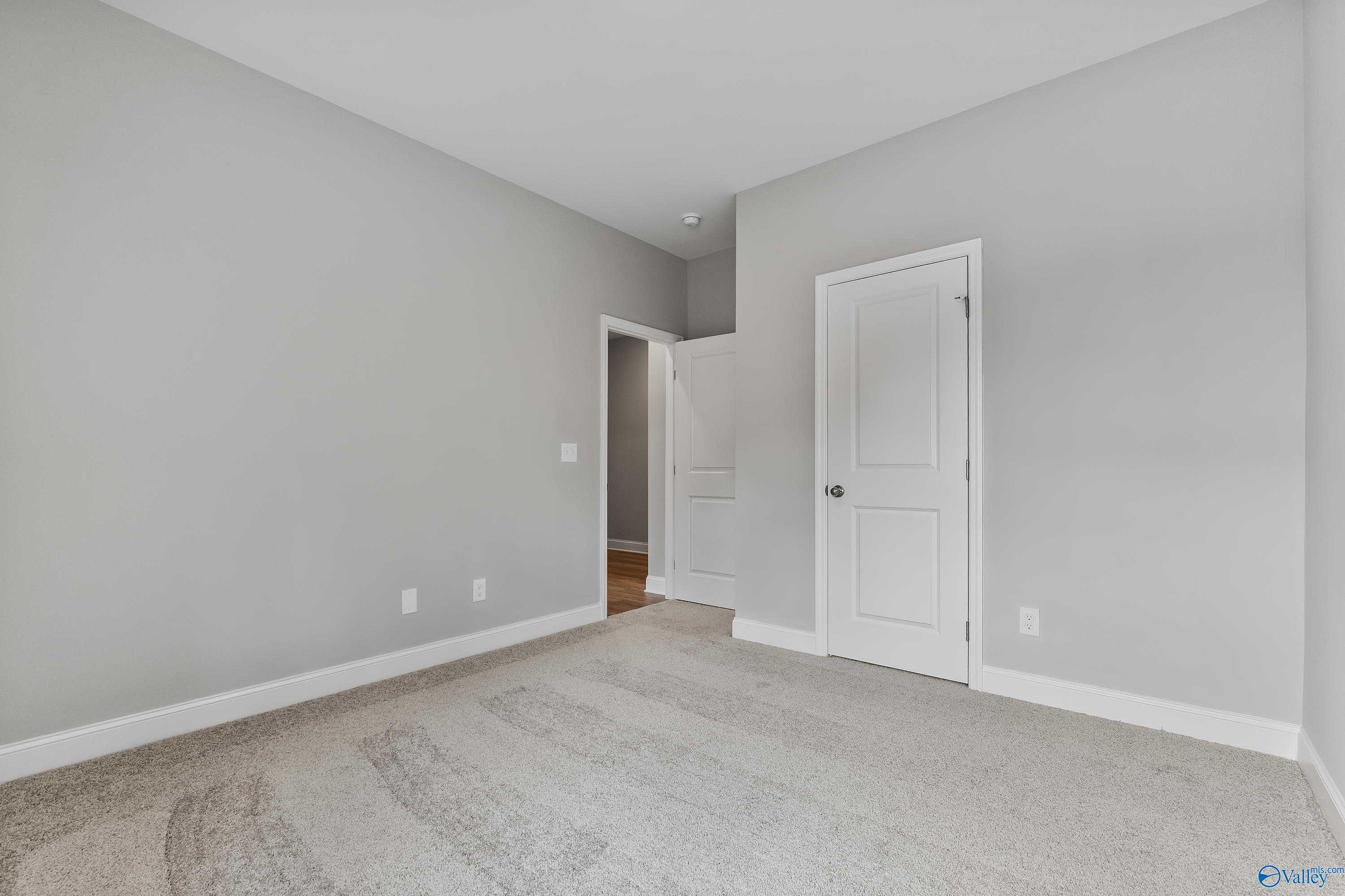 Spacious bedroom with gray walls, white doors, and plush carpet in The Franklin 3-bedroom home, Huntsville Alabama