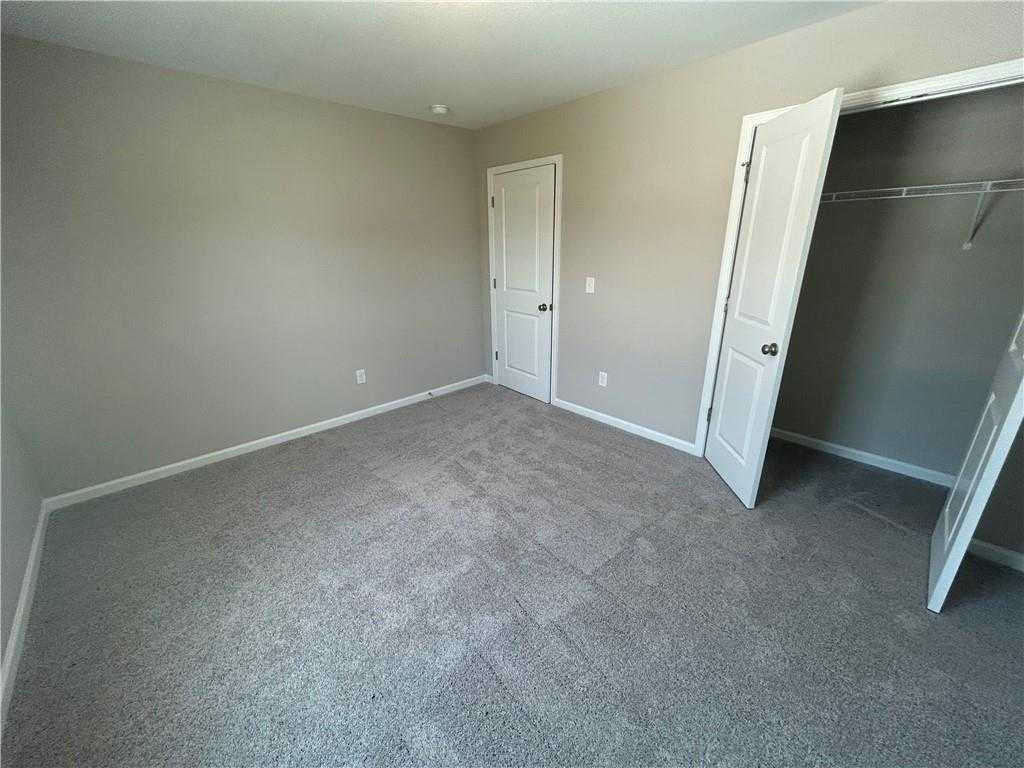 Spacious bedroom with beige walls, gray carpet, open closet door in Davidson Homes The Washington, Phenix City, Alabama