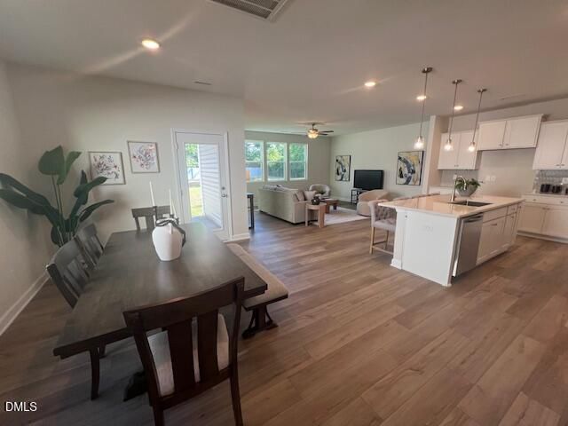 Open-concept living-dining-kitchen with hardwood floors, white cabinetry, and natural light in 4-bedroom Preston A home, Lillington, NC