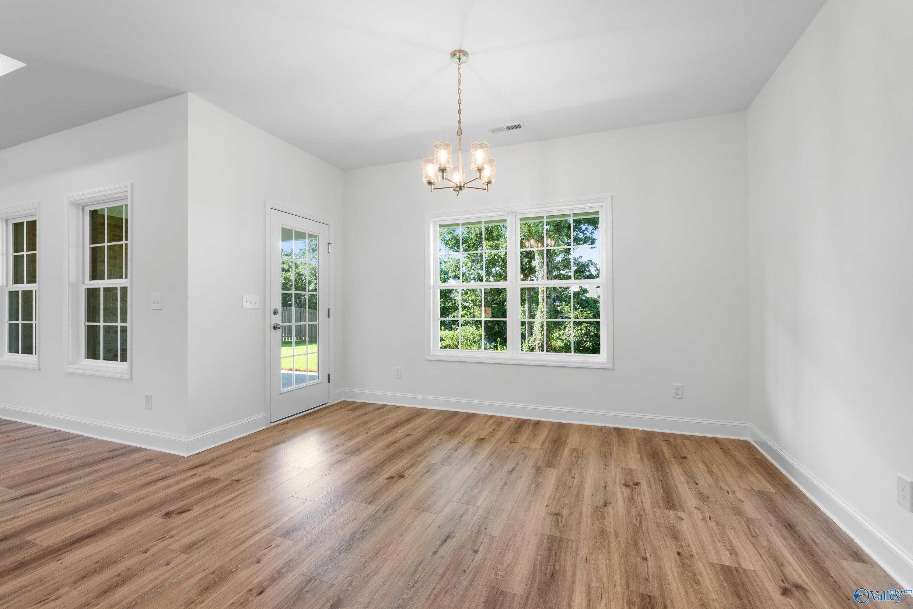Bright dining room with chandelier, large windows, glass door to yard, and hardwood floors in Davidson Homes The Oxford, Harvest AL