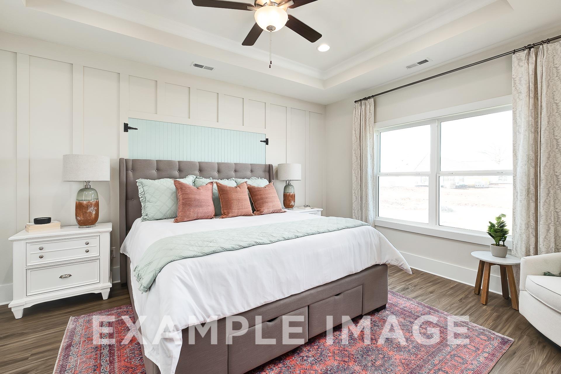Spacious master bedroom in The Everett B with tufted gray headboard, ceiling fan, large windows, and neutral decor