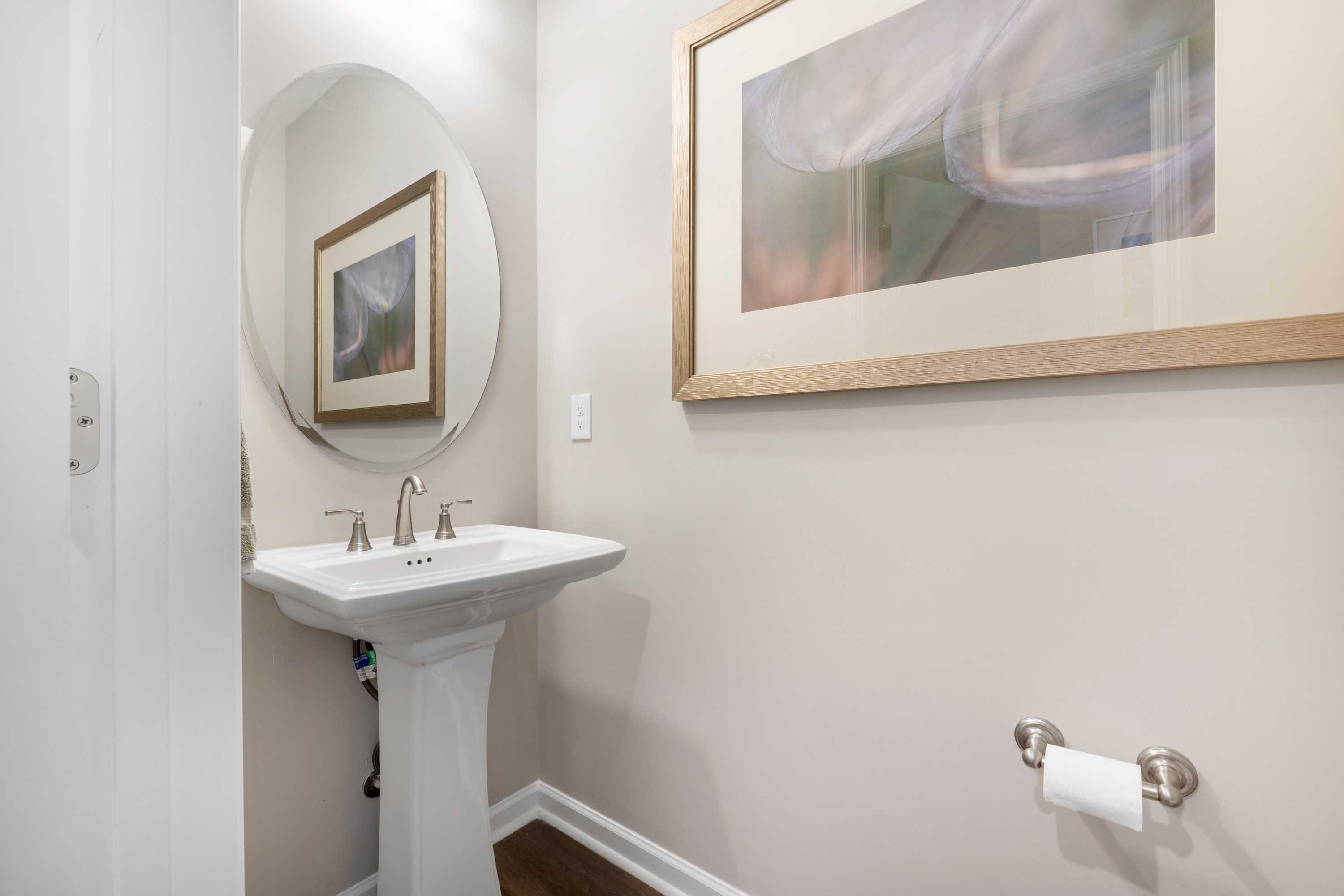 Elegant powder room in Evergreen Mill Madison AL with white pedestal sink round mirror and abstract art