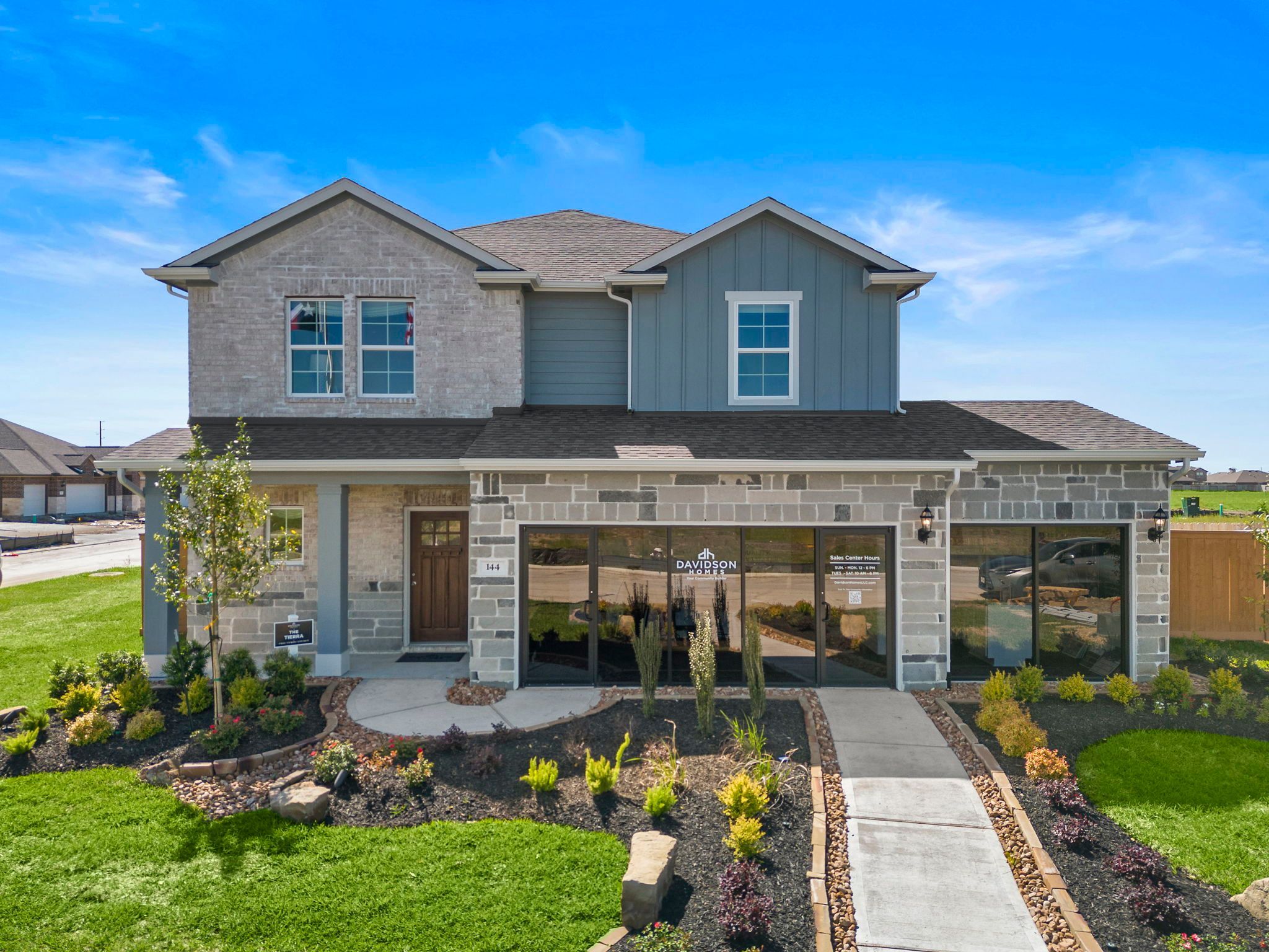 Spacious open-concept living room at River Ranch Meadows in Dayton Texas with modern gas fireplace, TV wall, cozy sofas and large potted plant