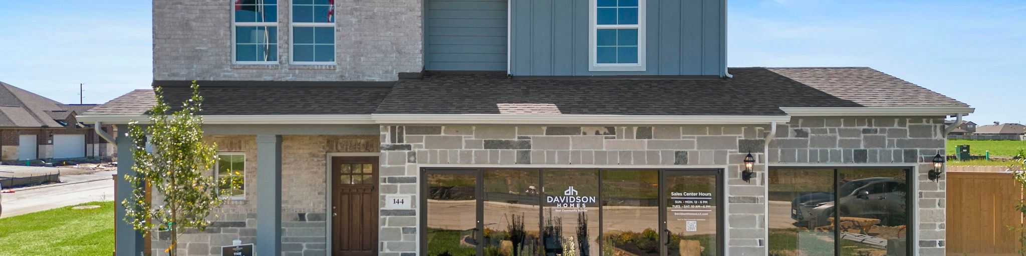 Spacious open-concept living room at River Ranch Meadows in Dayton Texas with modern gas fireplace, TV wall, cozy sofas and large potted plant