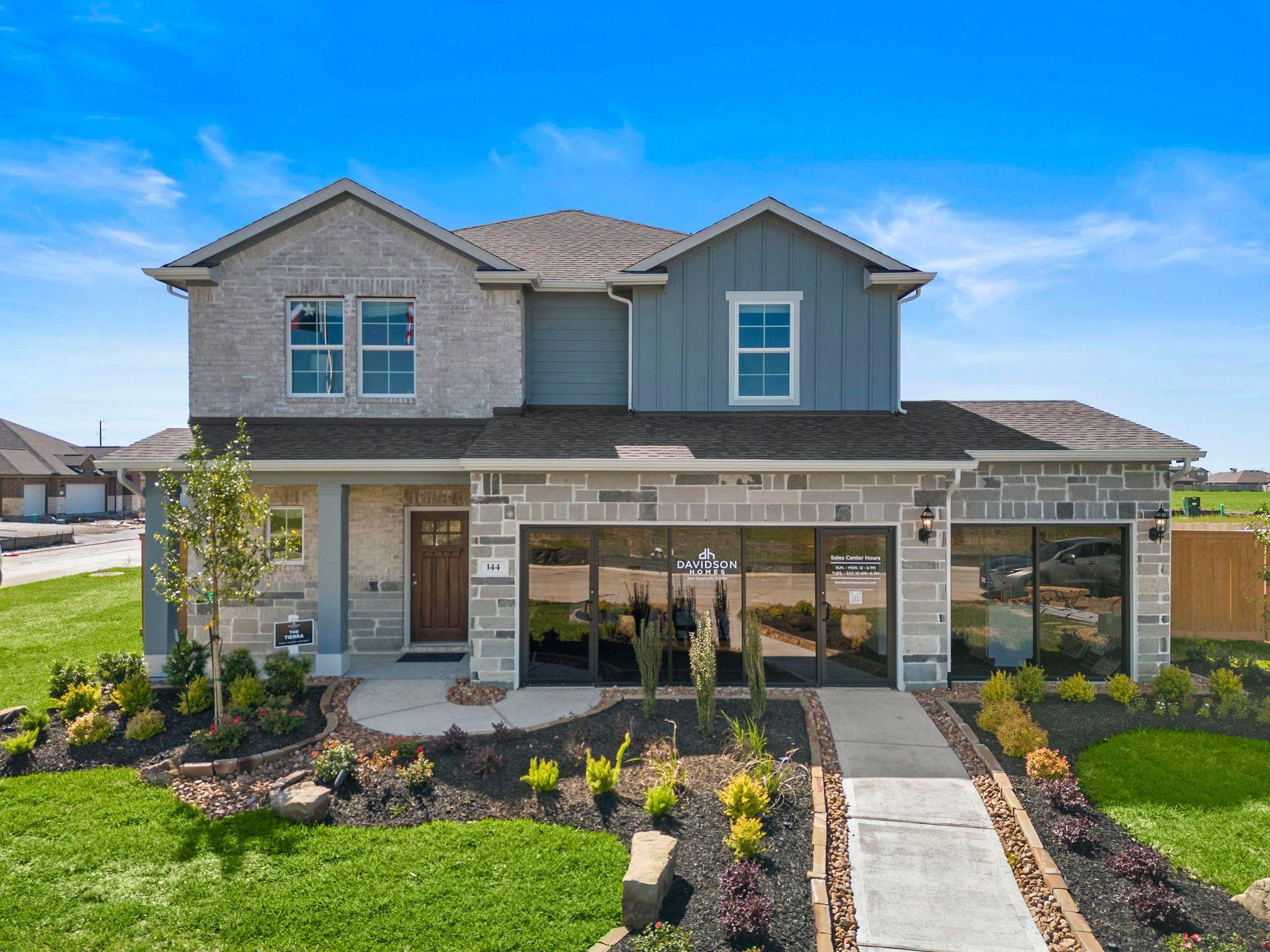 Spacious open-concept living room at River Ranch Meadows in Dayton Texas with modern gas fireplace, TV wall, cozy sofas and large potted plant