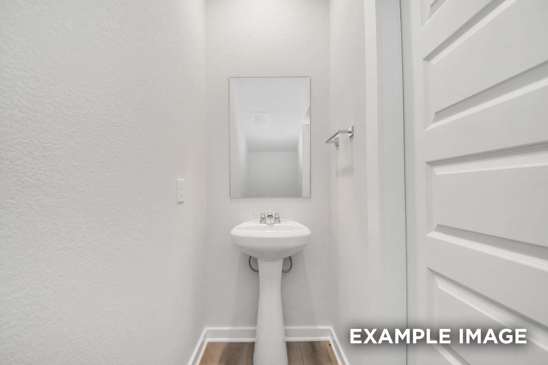 White pedestal sink with frameless mirror in half bath of Davidson Homes The Blanco E floor plan, Windmill Estates, Magnolia, Texas