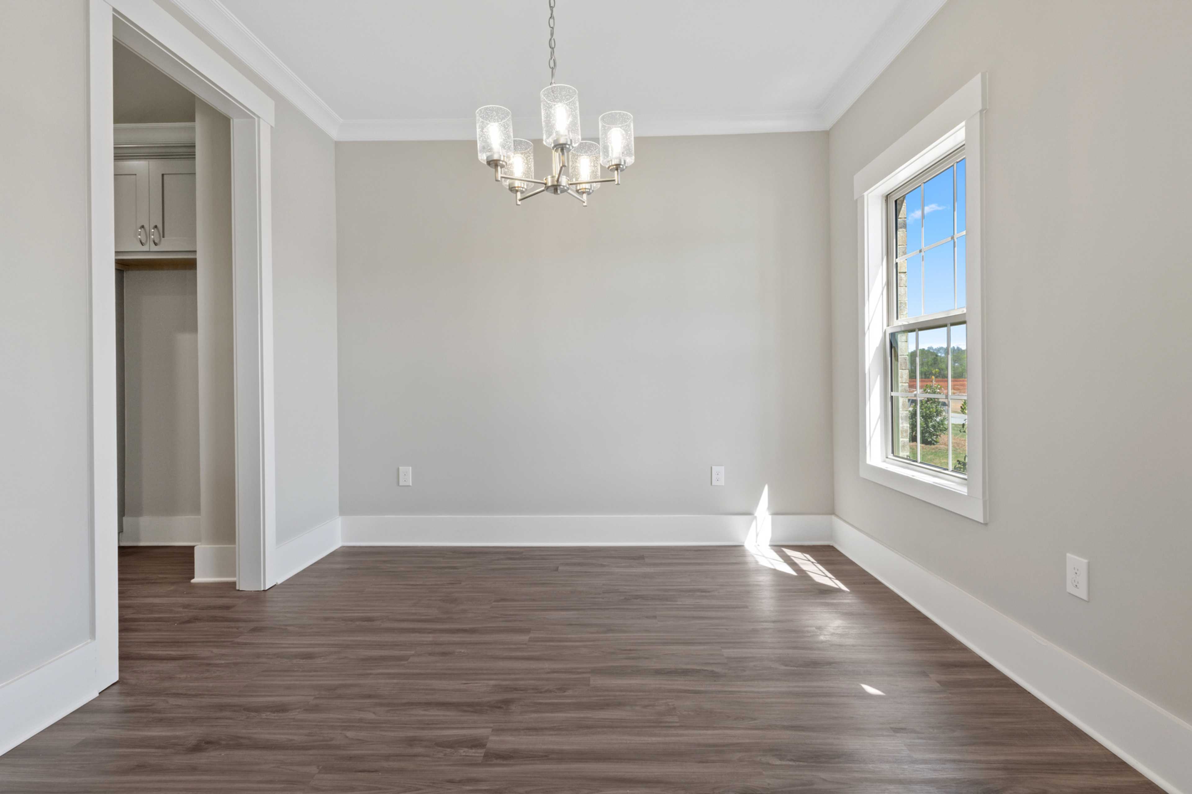 Spacious empty dining room in Little Burwell Estates Harvest AL with hardwood floors modern chandelier and large sunny window