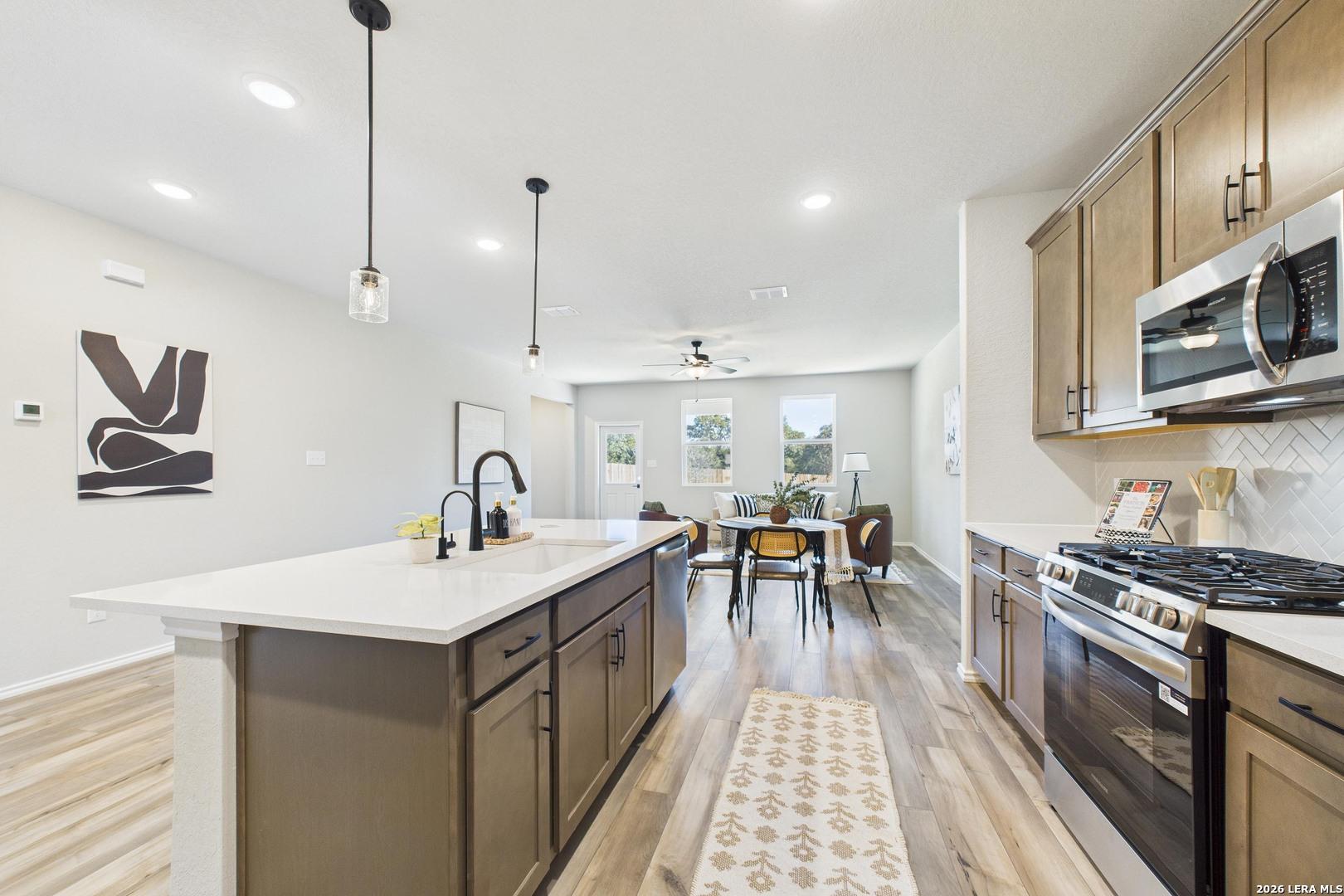 Modern open-concept kitchen with white island, stainless appliances, and dining nook in Davidson Homes The Douglas E, Bricewood, San Antonio