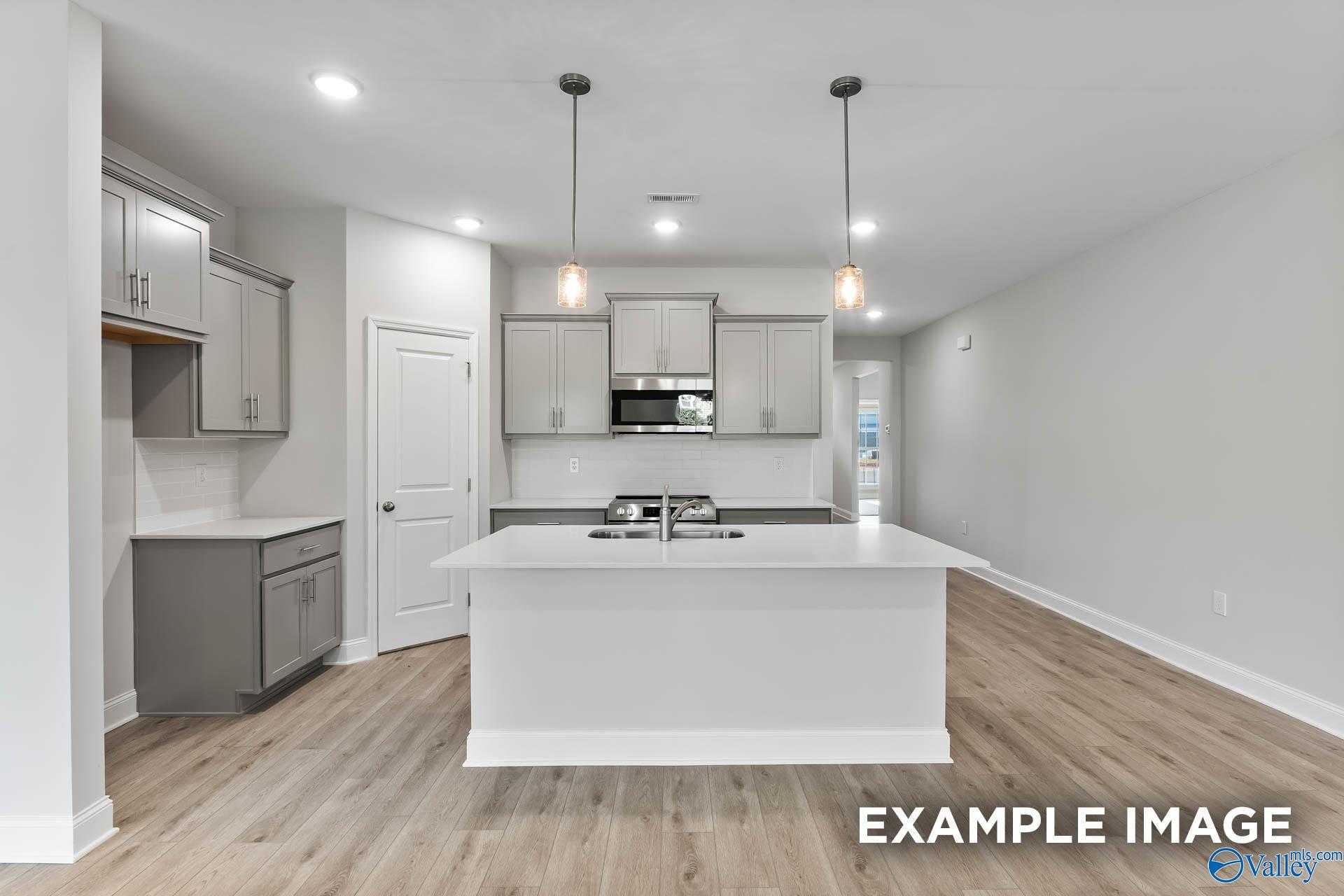 Modern kitchen featuring white island, stainless appliances, gray cabinets in The Daphne C floor plan, Davidson Homes, New Market, AL