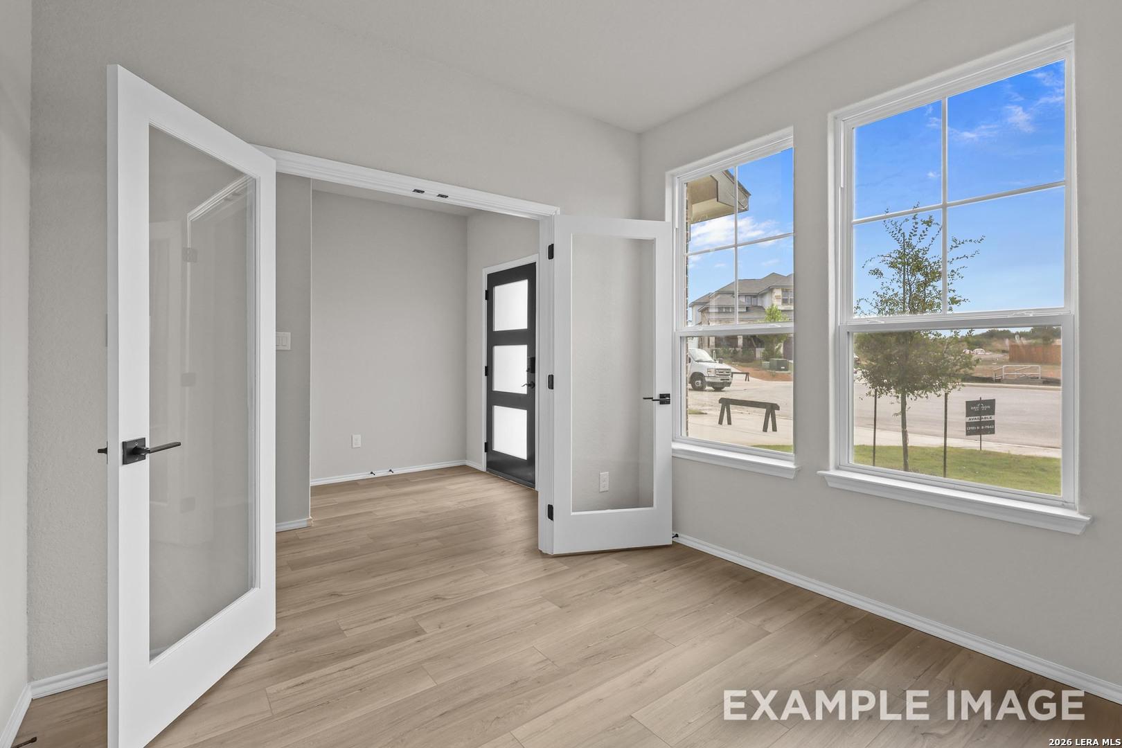 Bright flex room with glass French doors, wood-look flooring, and large windows in Davidson Homes The Murray H, Converse, Texas