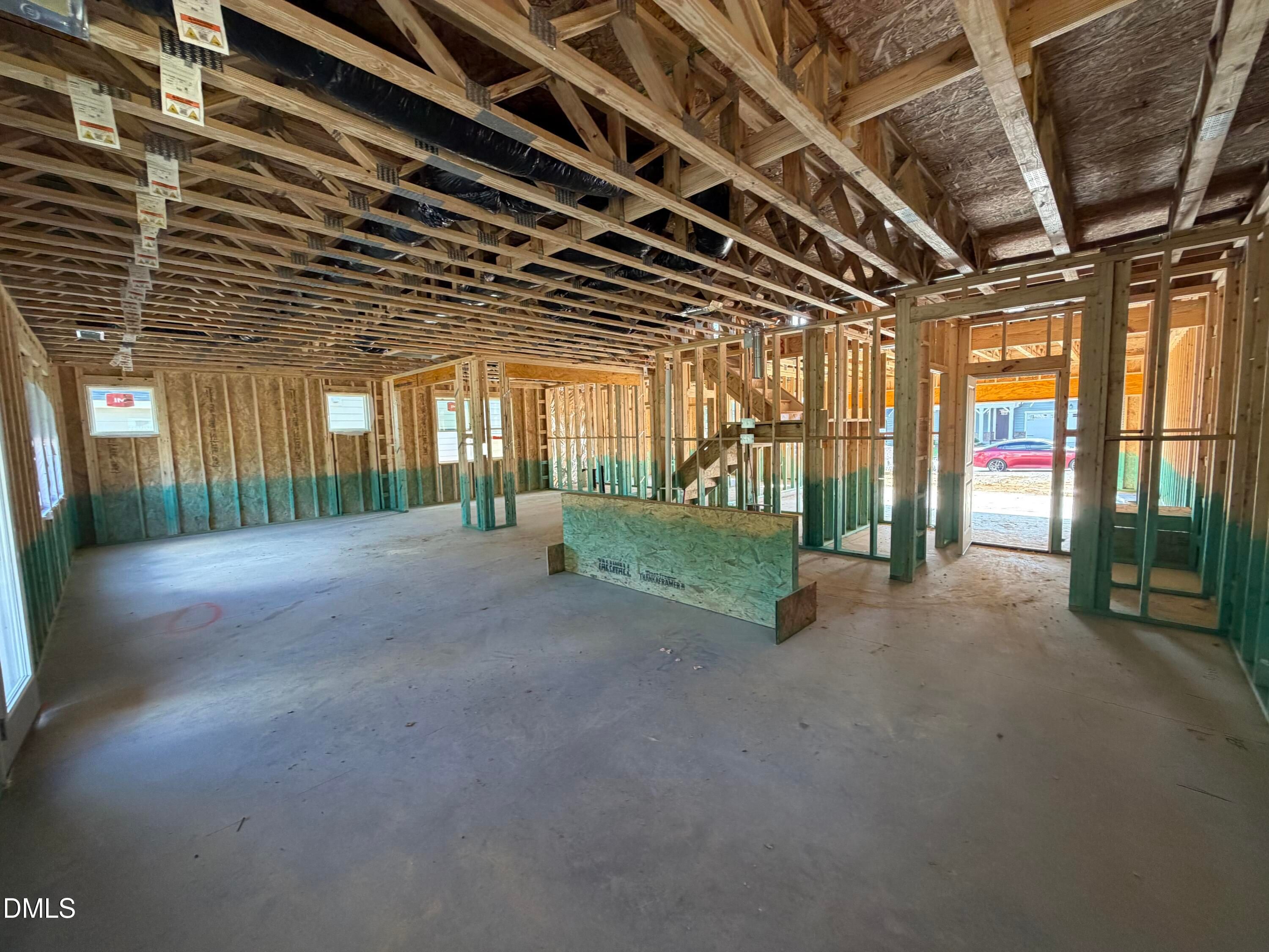 Framing under construction showing open-concept floor plan with exposed trusses and stairs in Davidson Homes The Beech, Wendell Ridge
