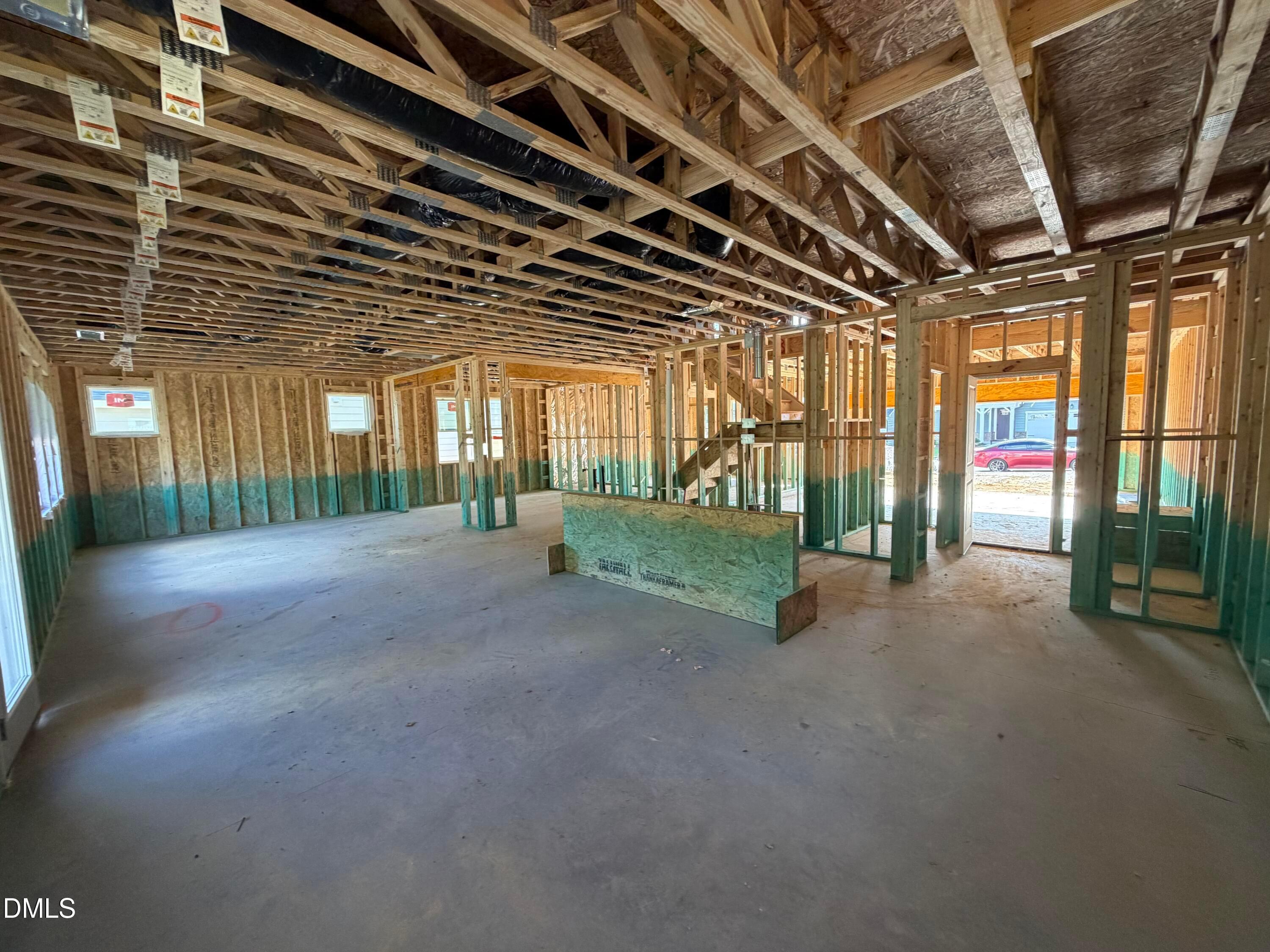 Framing under construction showing open-concept floor plan with exposed trusses and stairs in Davidson Homes The Beech, Wendell Ridge