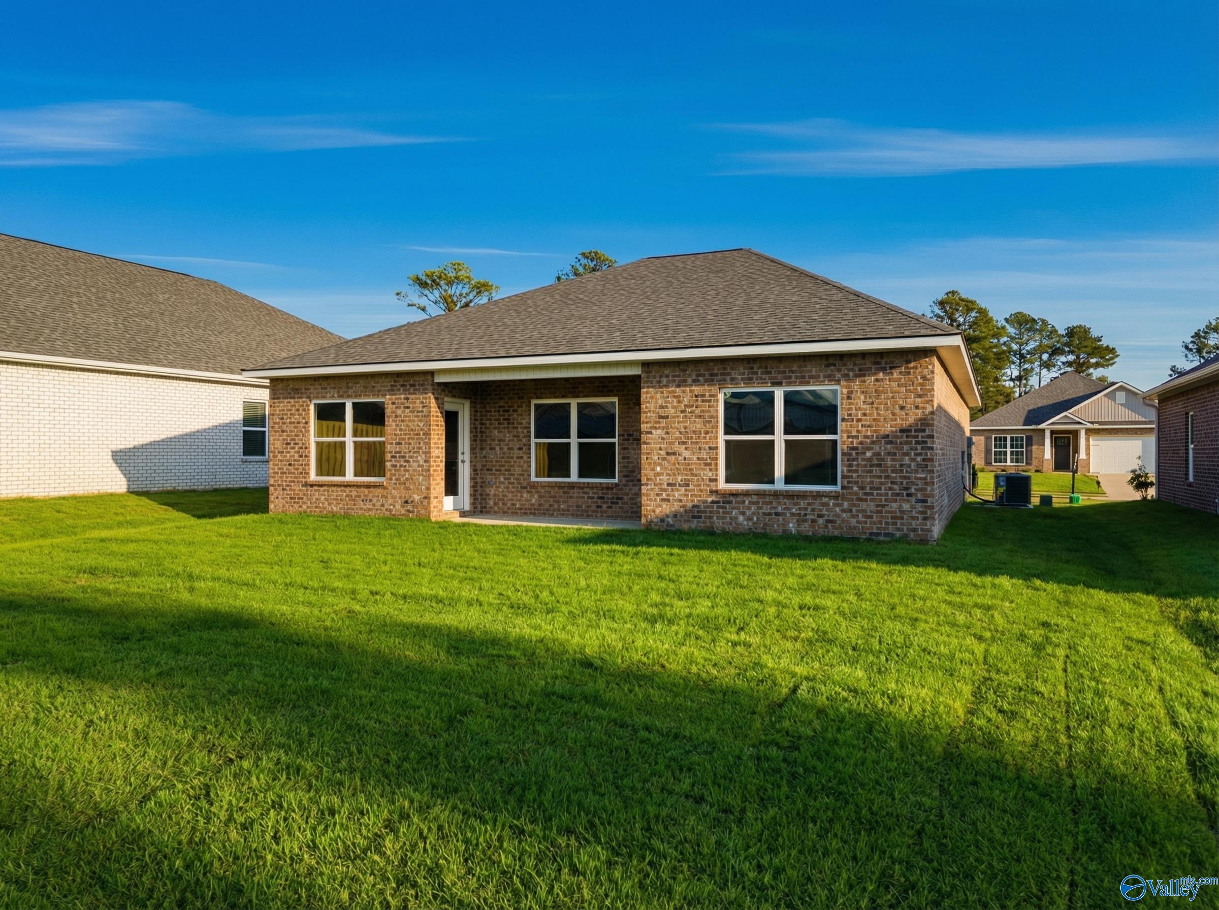 Single-story brick home with large windows, attached garage, and lush green lawn in Jaguar Hills, Huntsville, Alabama