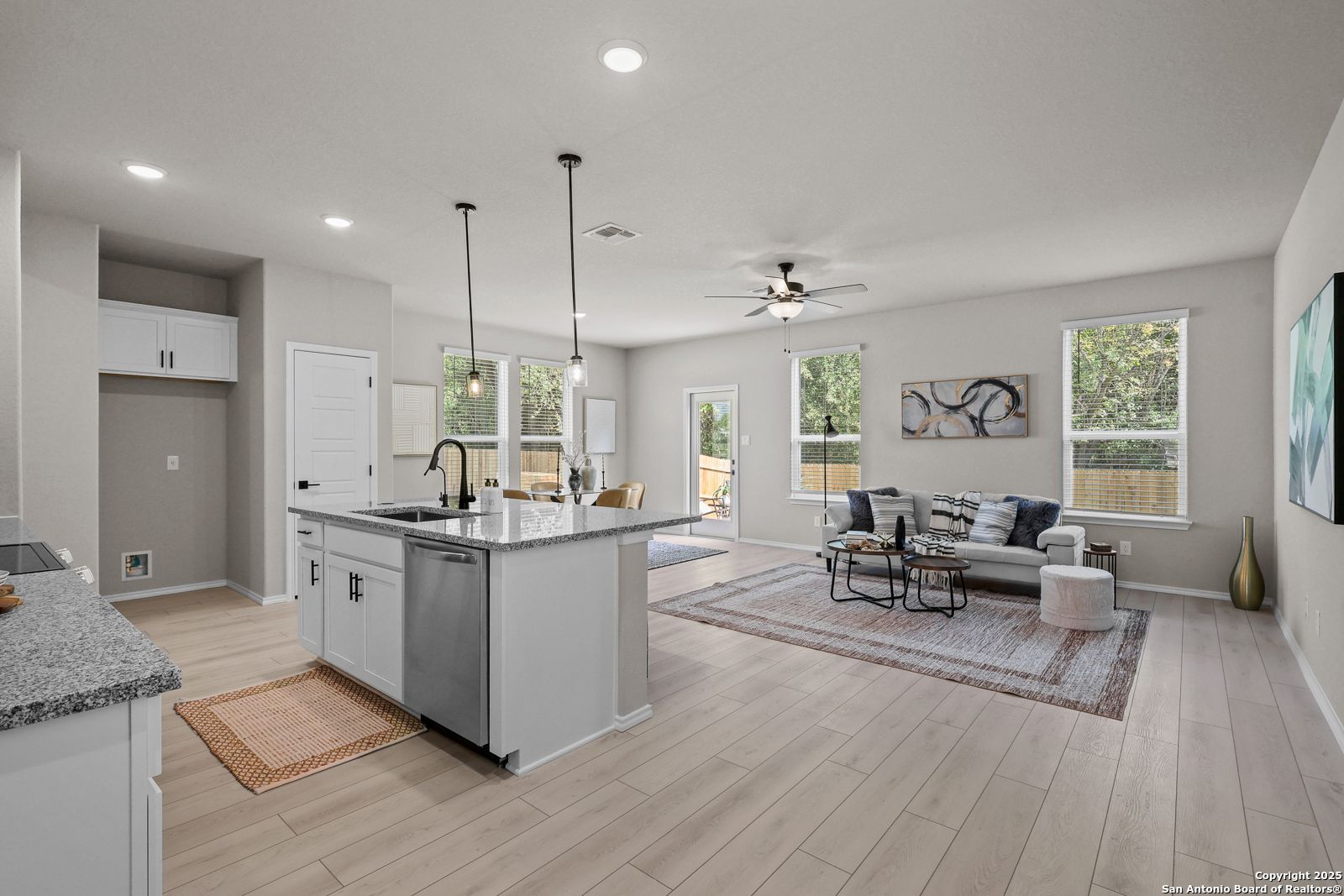 Modern open-concept kitchen and living room with granite island, stainless appliances, hardwood floors in Davidson Homes The Charlotte B, San Antonio, TX