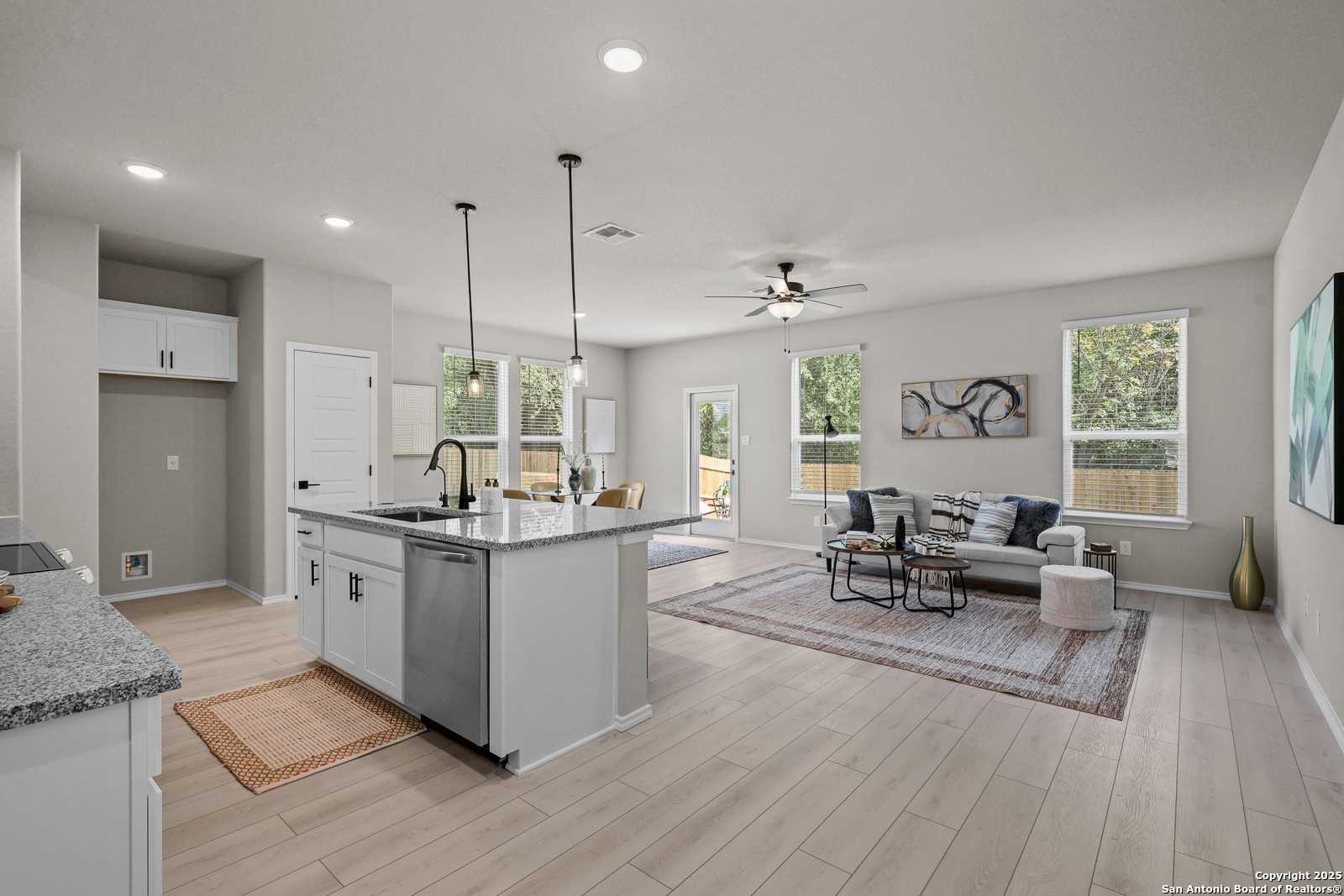 Modern open-concept kitchen and living room with granite island, stainless appliances, hardwood floors in Davidson Homes The Charlotte B, San Antonio, TX