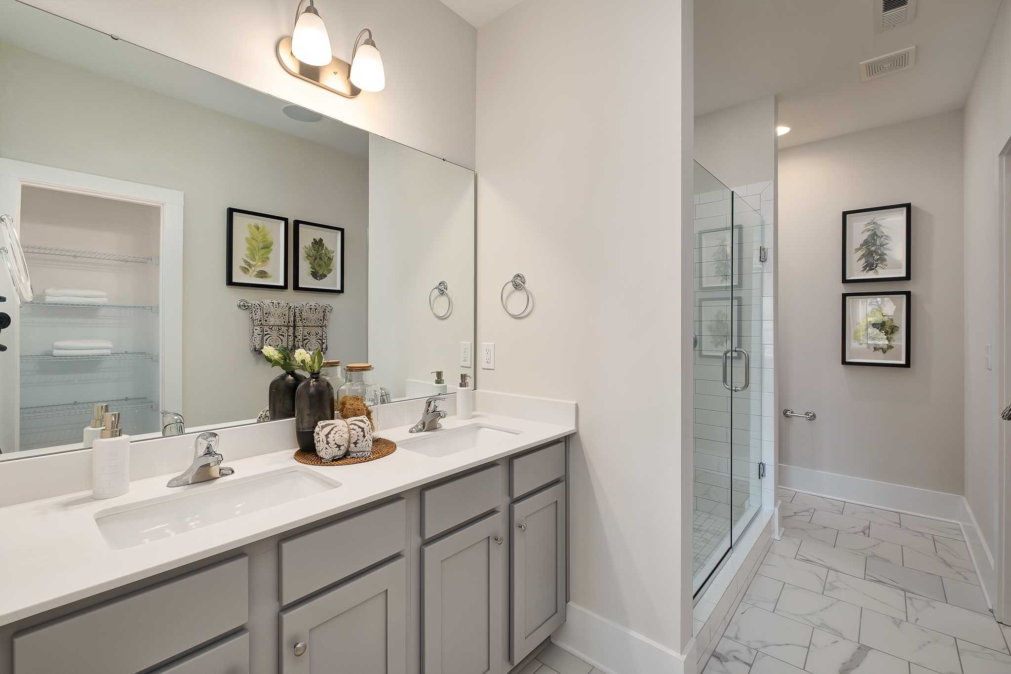 Spacious modern bathroom at Magnolia Preserve in Hartselle Alabama with double vanity gray cabinets quartz counters and glass shower