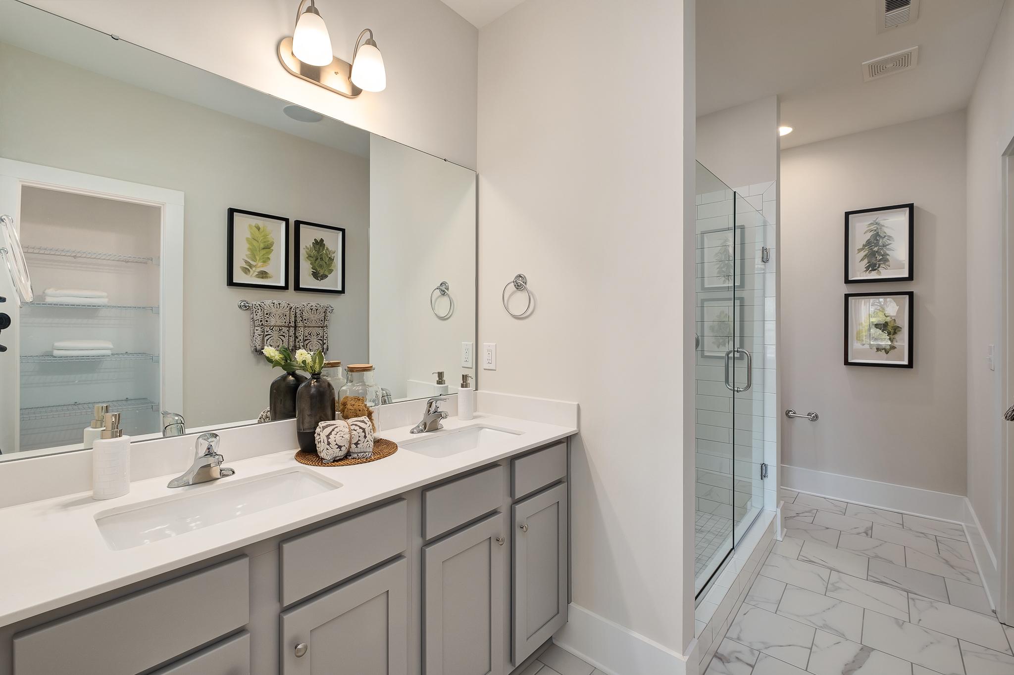 Spacious modern bathroom at Magnolia Preserve in Hartselle Alabama with double vanity gray cabinets quartz counters and glass shower